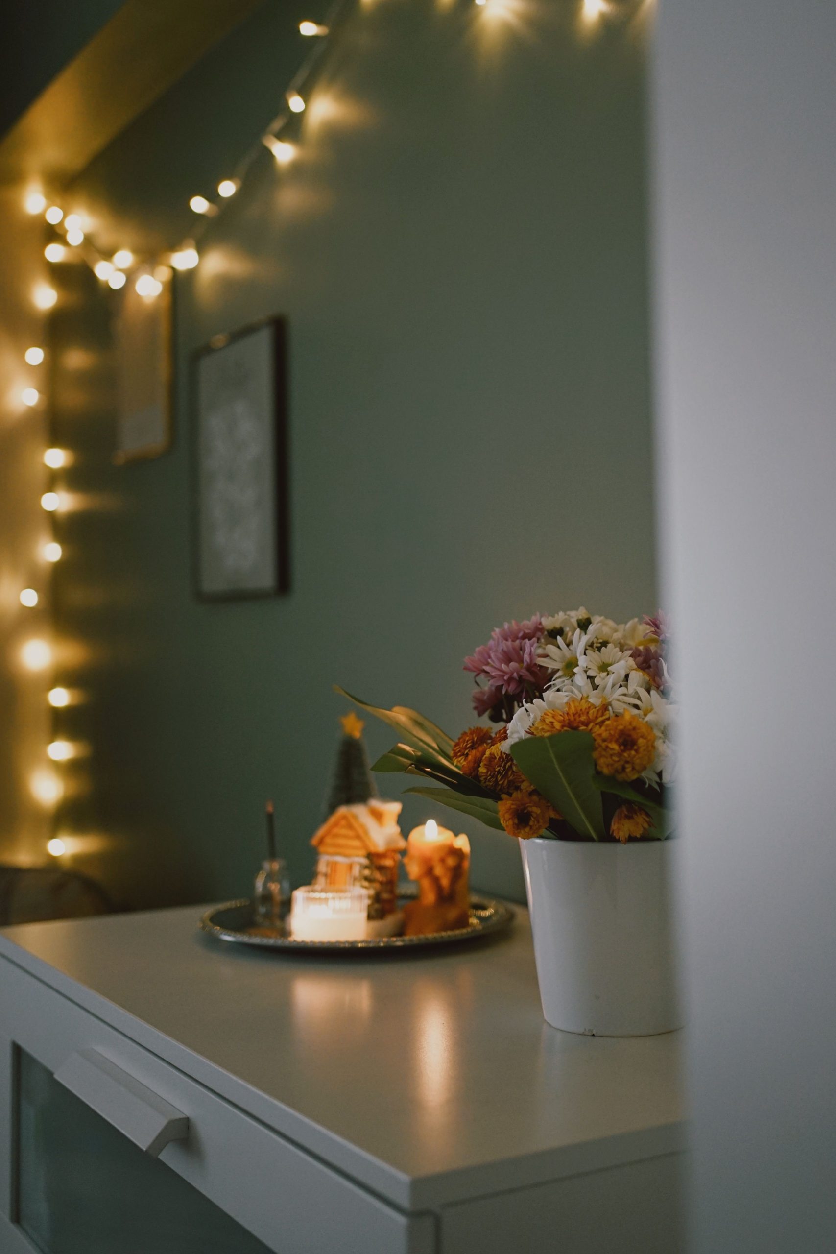Warm indoor scene with flowers, fairy lights, and cozy decorations.