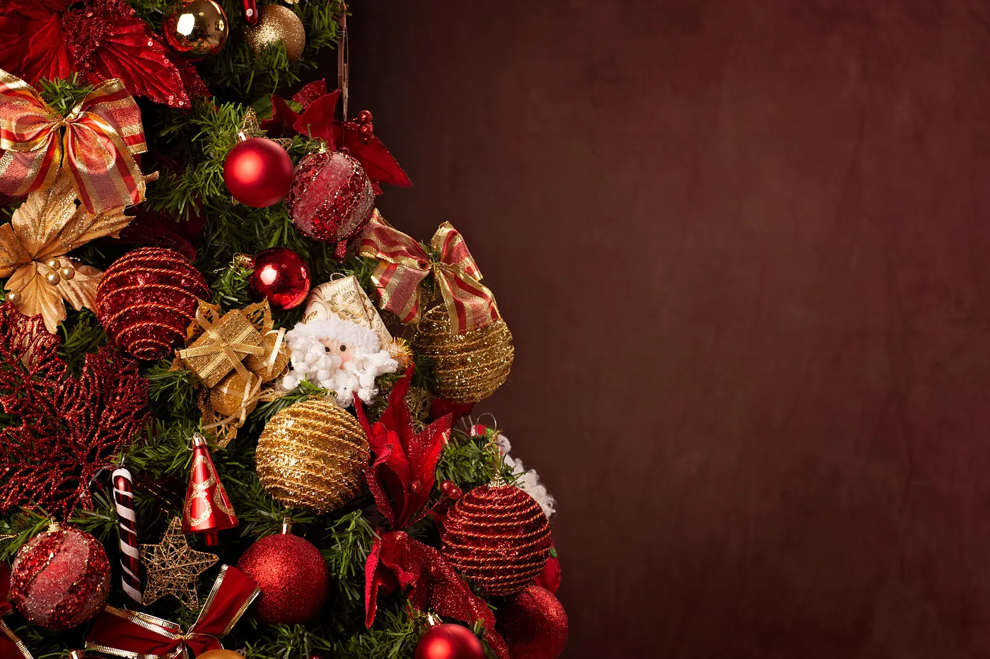A beautifully decorated Christmas tree featuring red and gold ornaments with ample copy space.