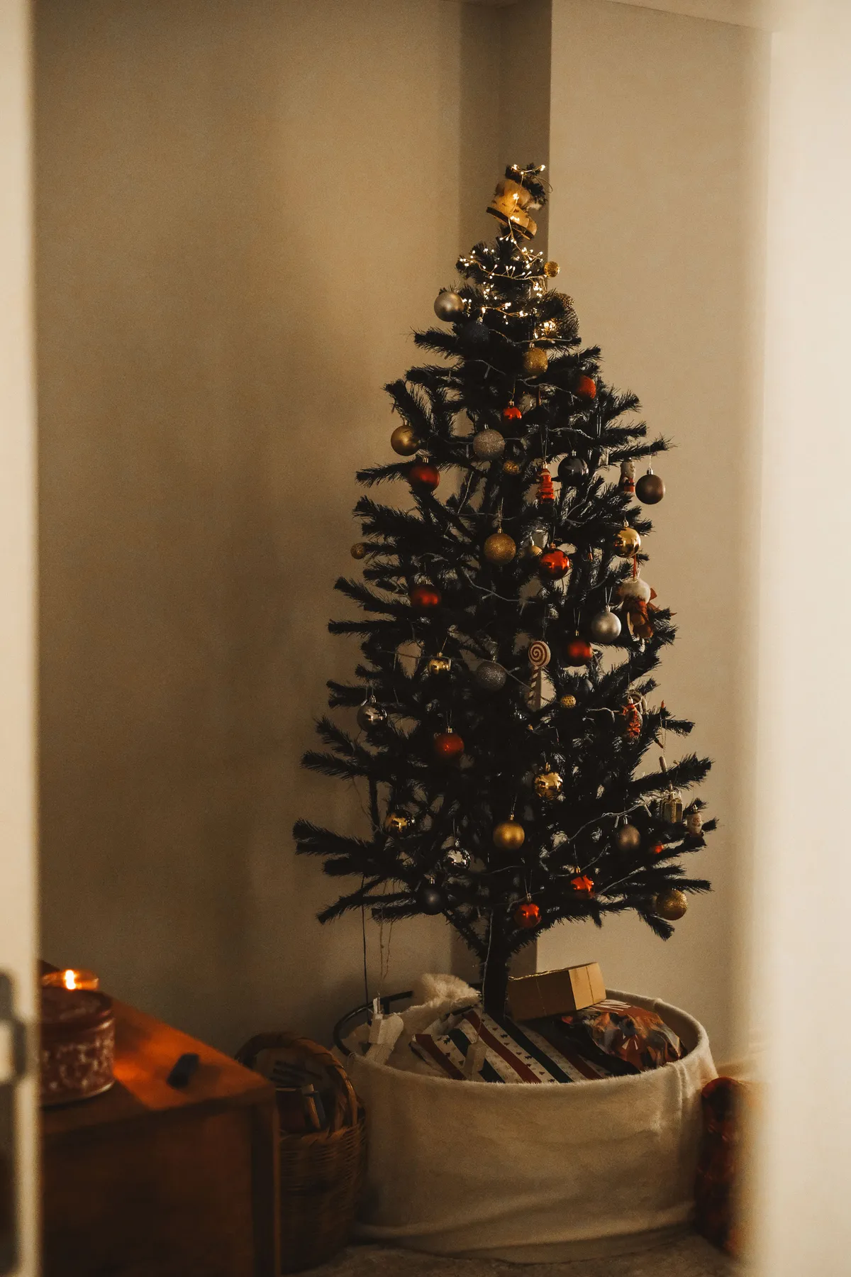 A beautifully decorated Christmas tree indoors with gifts and ornaments, creating a festive atmosphere.