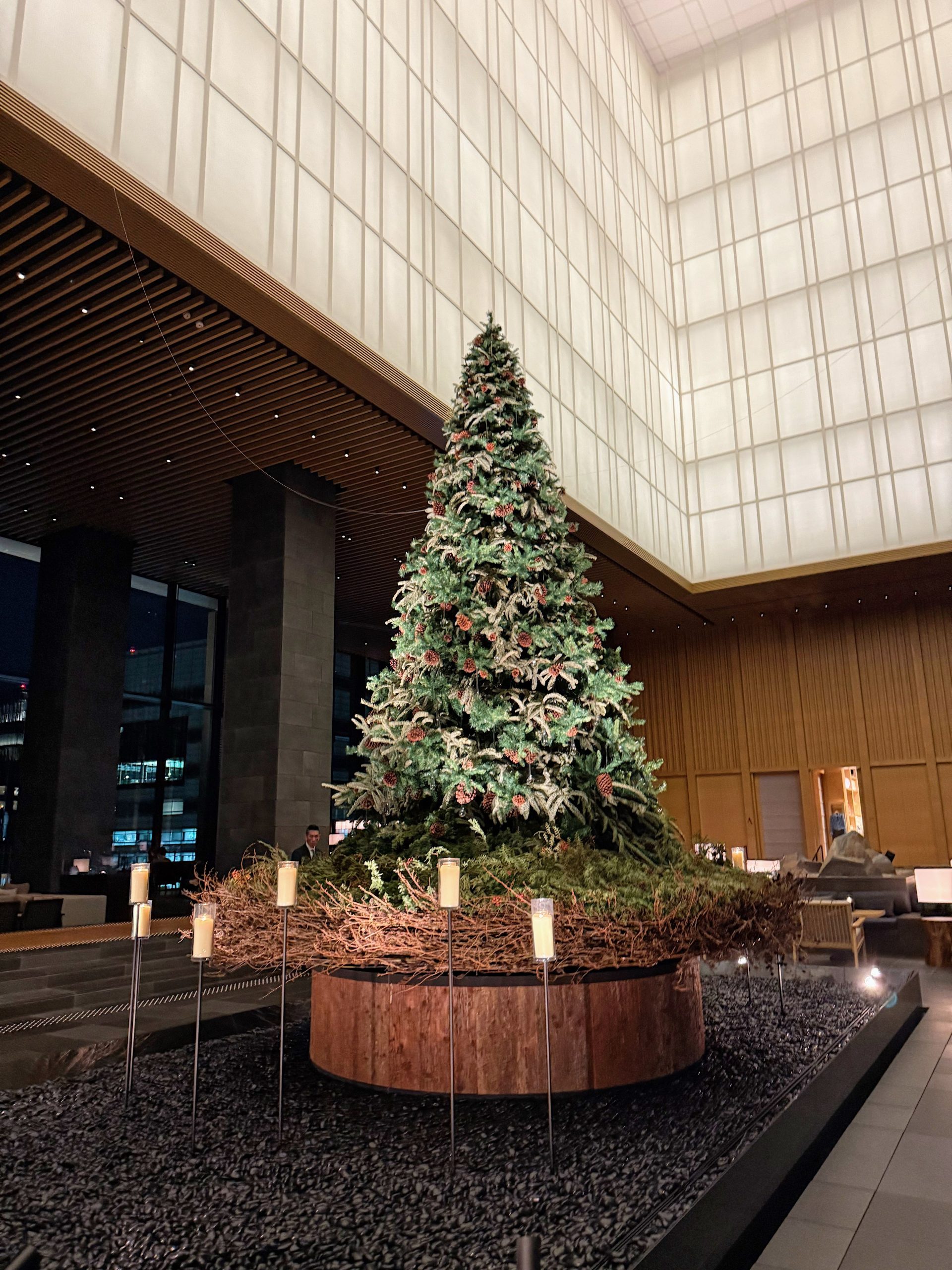 A beautifully decorated Christmas tree inside a modern building with warm lighting and elegant decor.