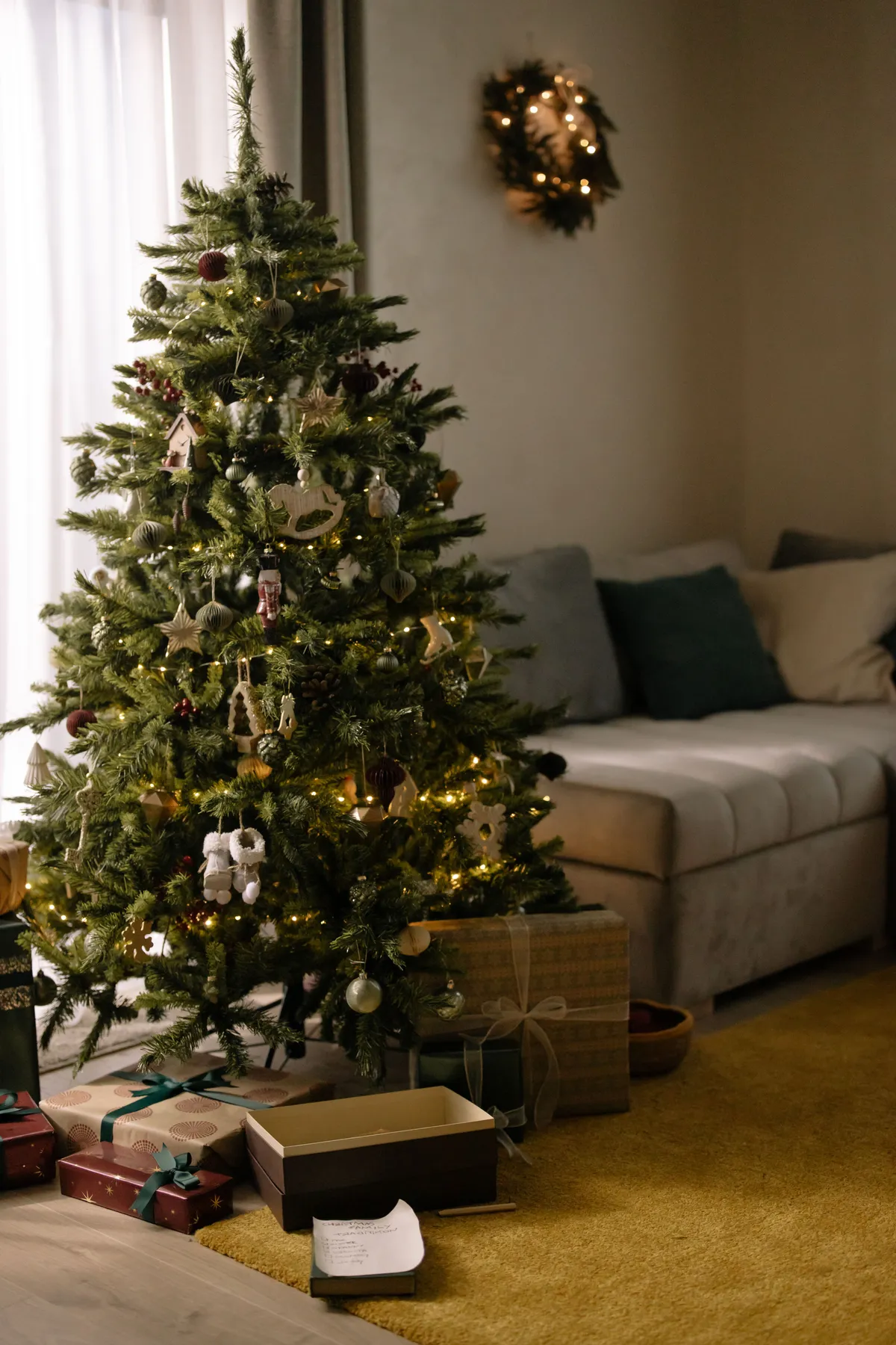 A beautifully decorated Christmas tree with glowing lights in a cozy living room setting.