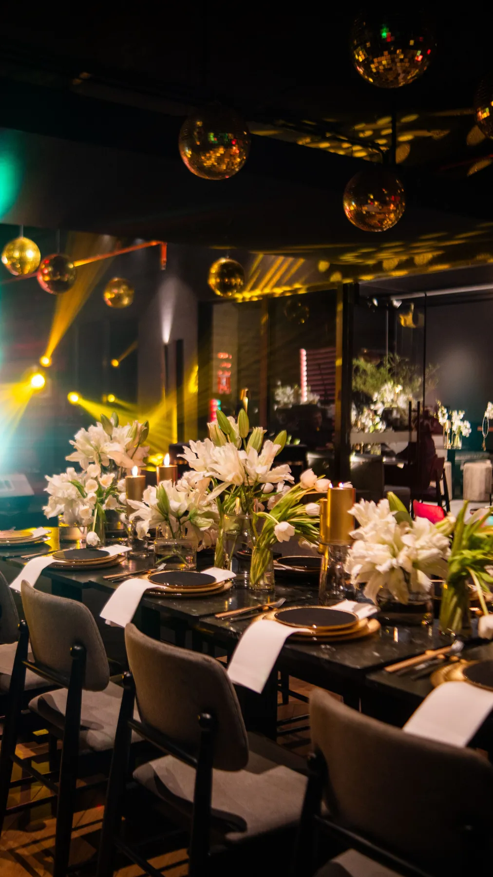 A beautifully set dinner table with floral arrangements and golden lighting, perfect for a party.