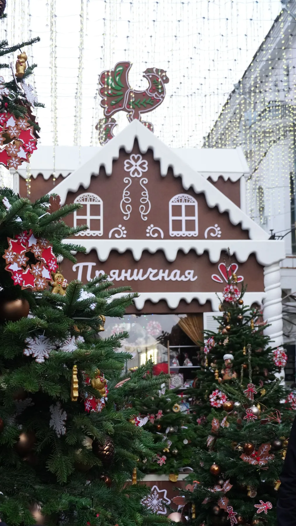 A charming gingerbread house at a winter Christmas market adorned with Christmas trees and decorations.
