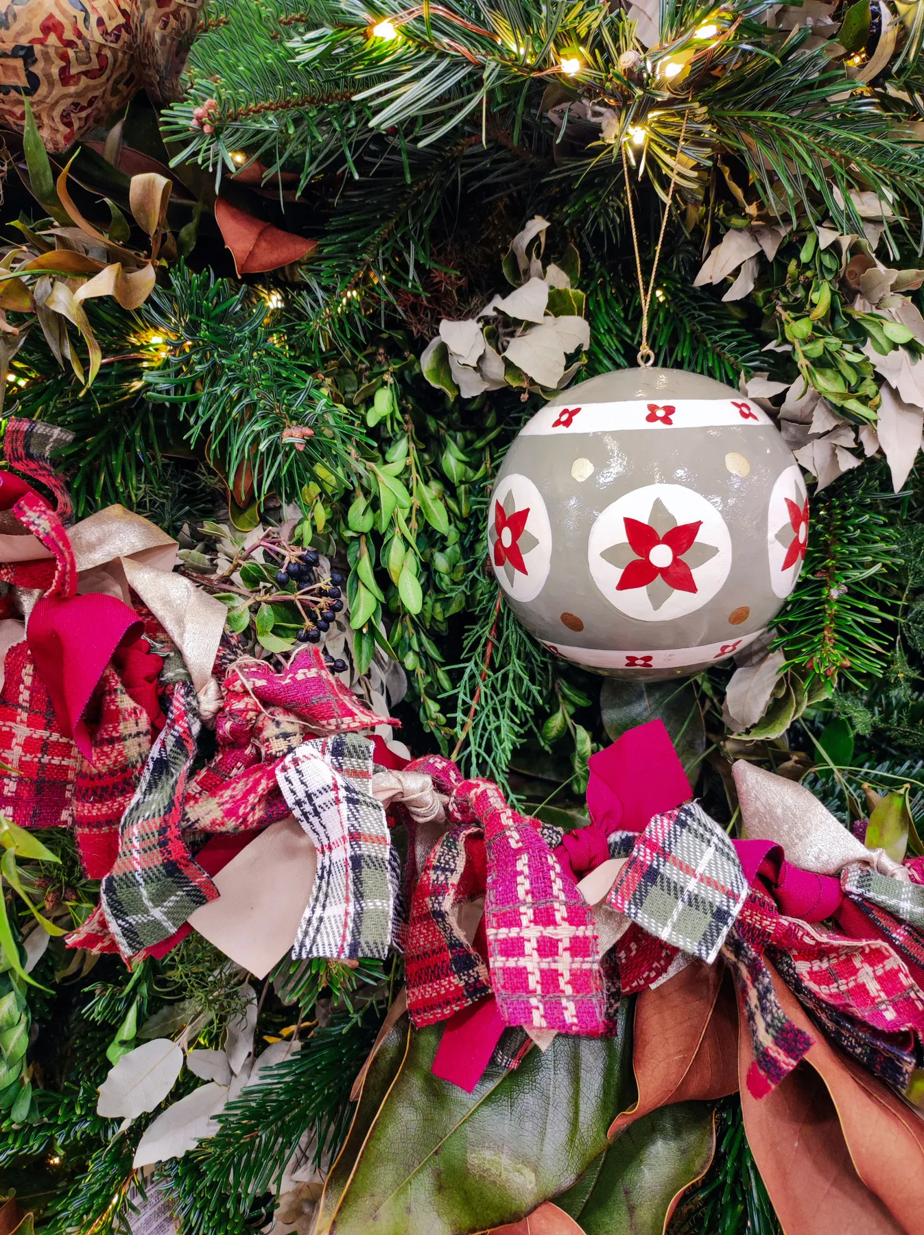 A close-up of a Christmas ornament hanging on a beautifully decorated tree with lights.