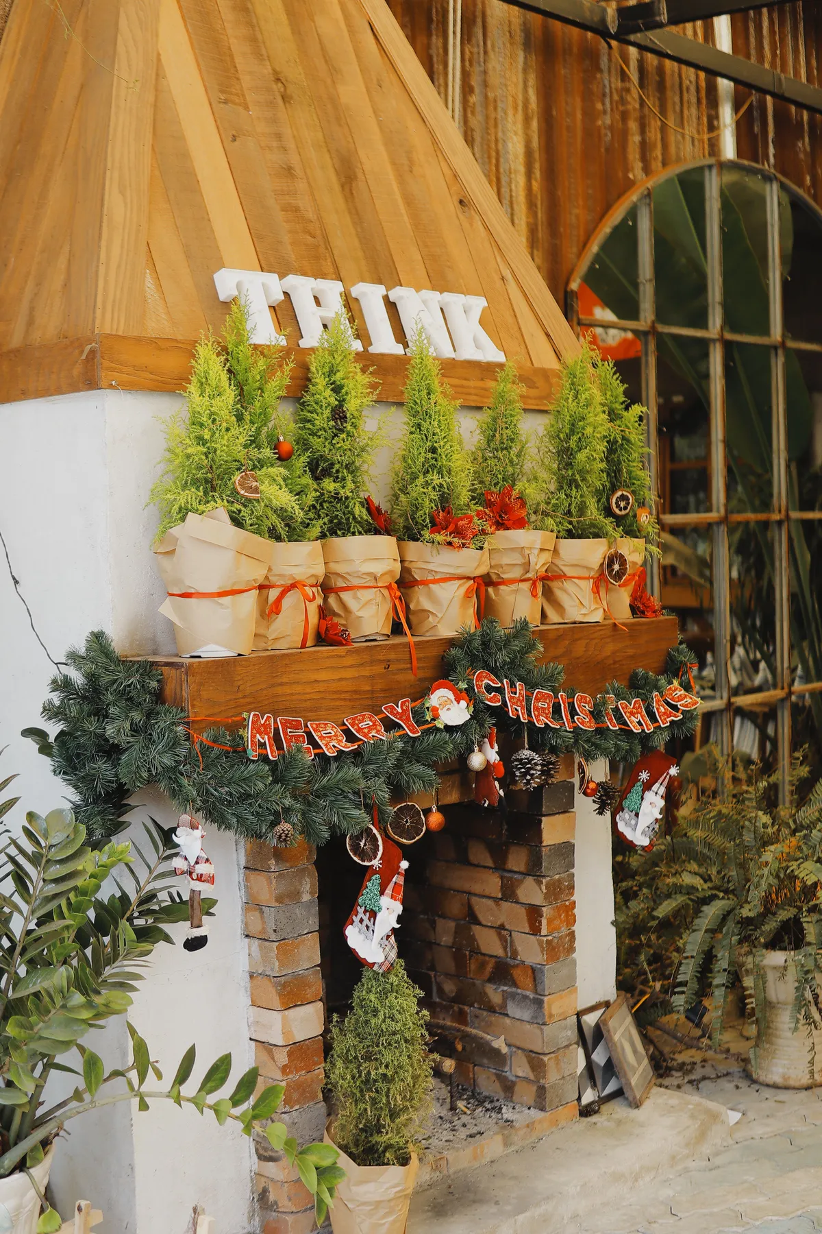 A cozy indoor fireplace decorated with Christmas trees and festive ornaments.