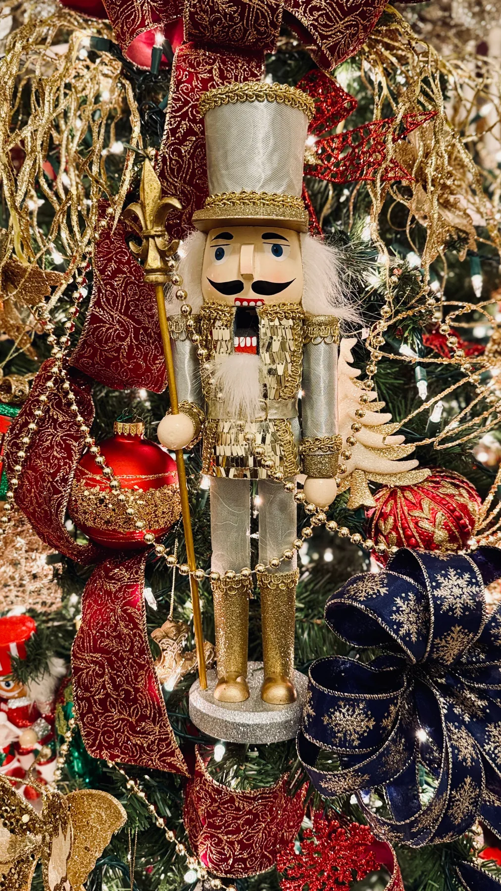 A decorative nutcracker in festive holiday colors on a Christmas tree.