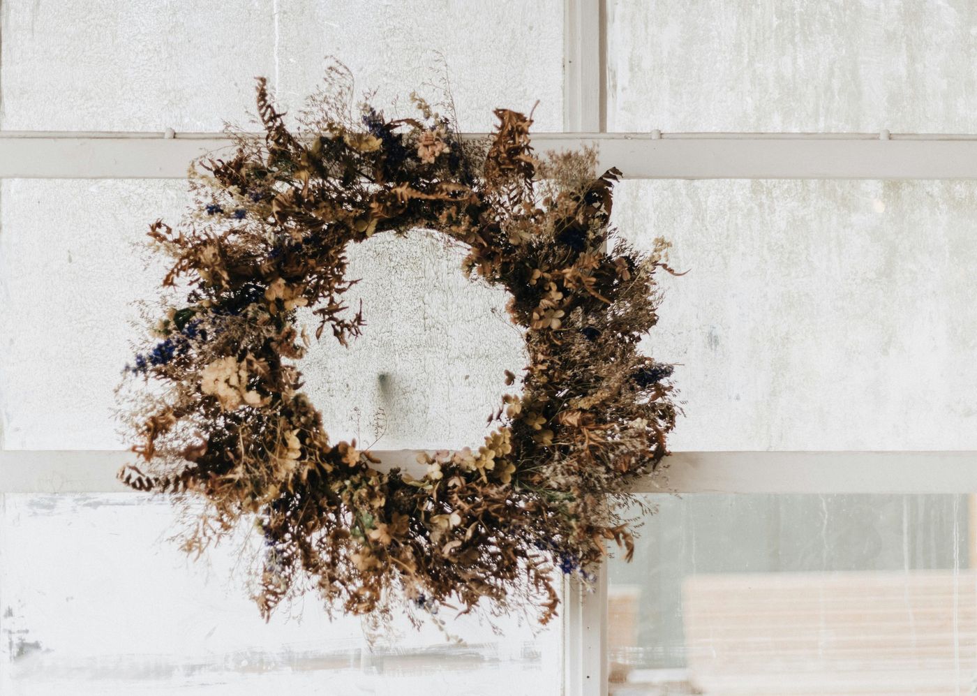 A dried wreath hanging on a window sill