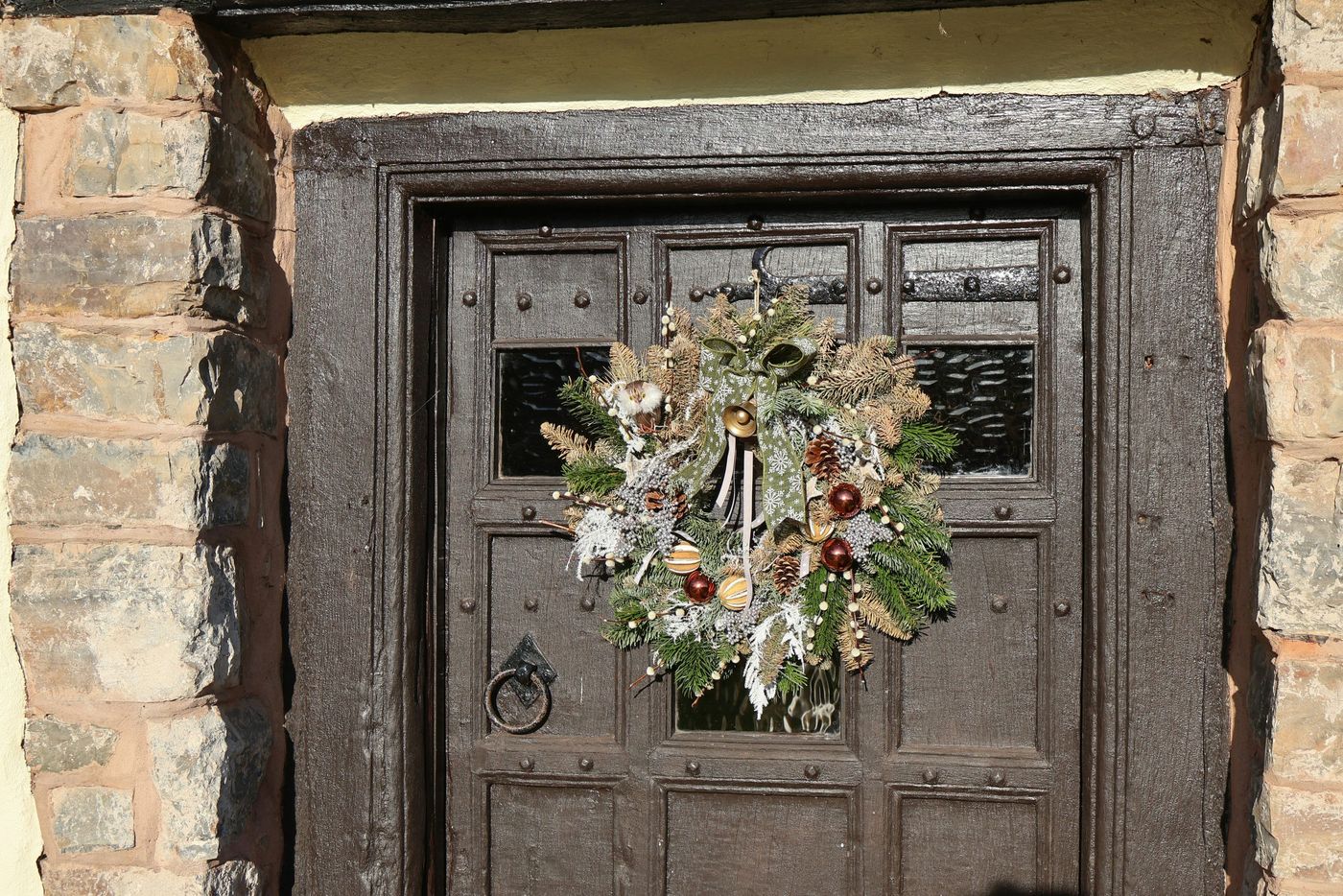 A festive wreath hangs on a rustic wooden door