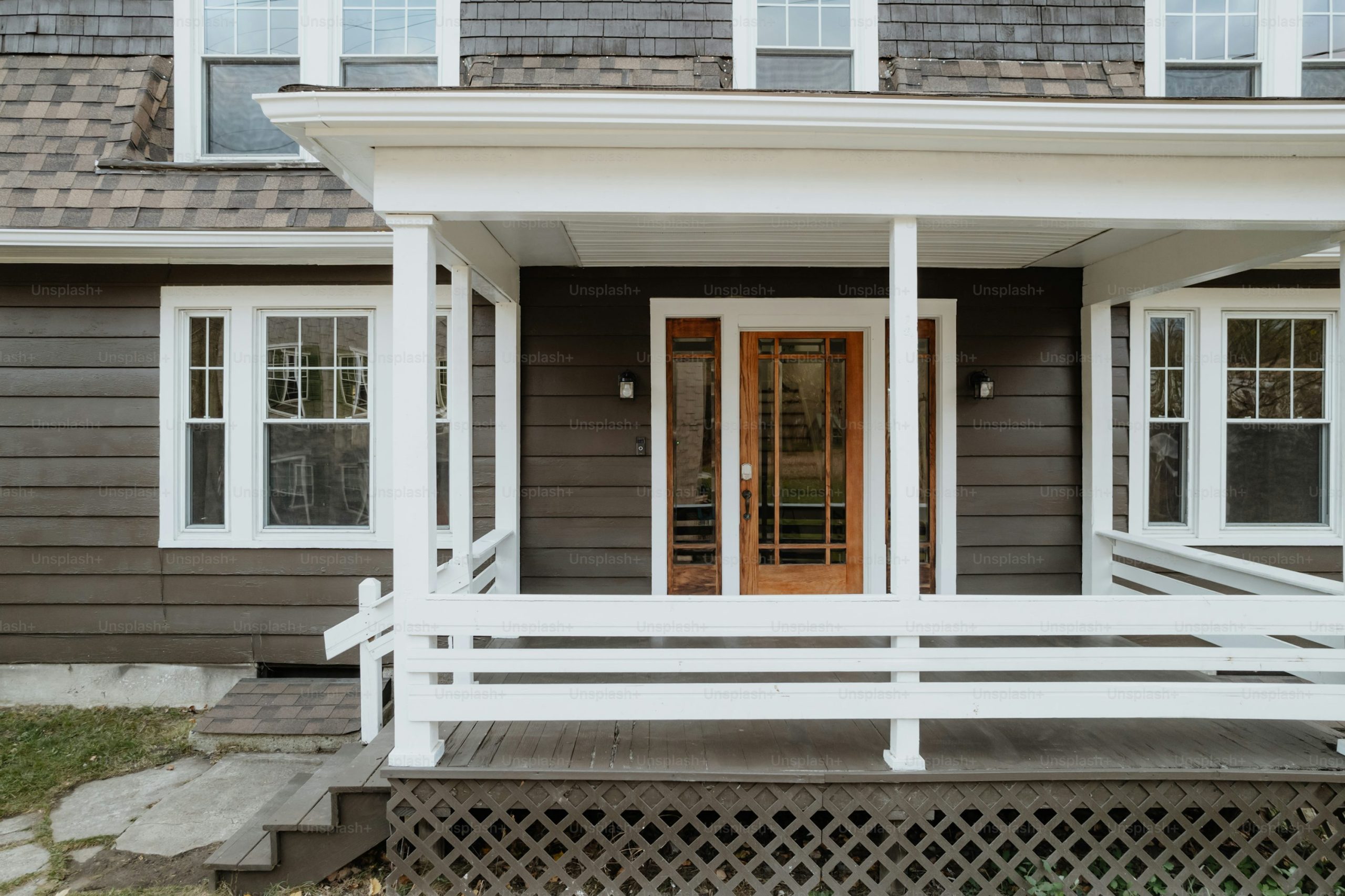 A gray house with white trim and a red door - Photo on Unsplash+