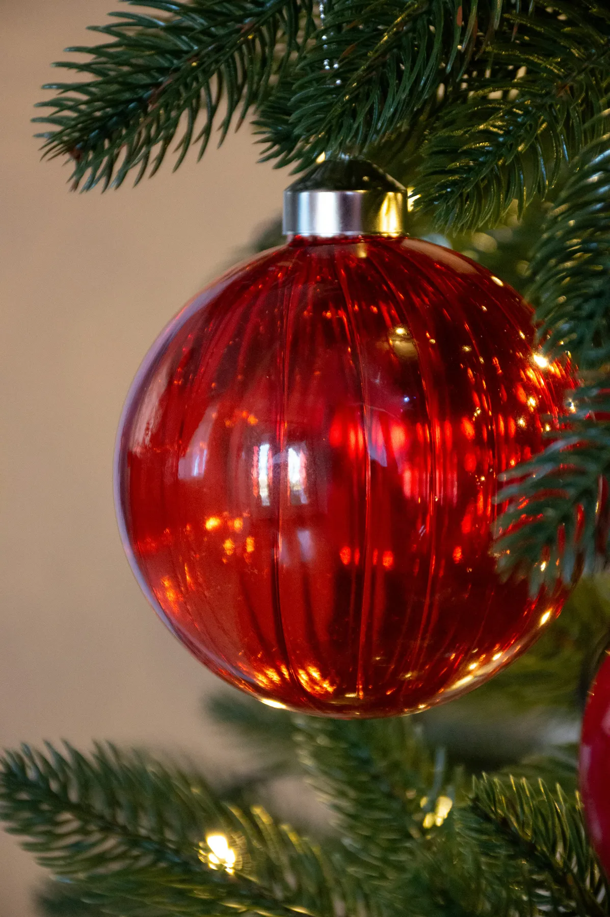 A red ornament hanging from a christmas tree