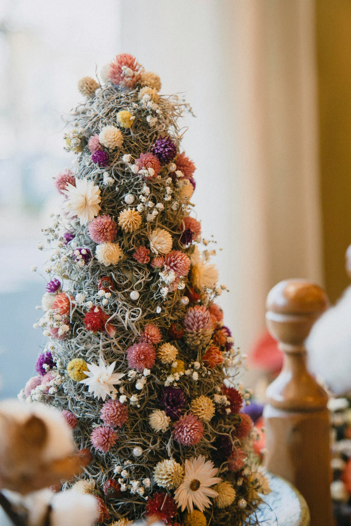 A small christmas tree is decorated with flowers
