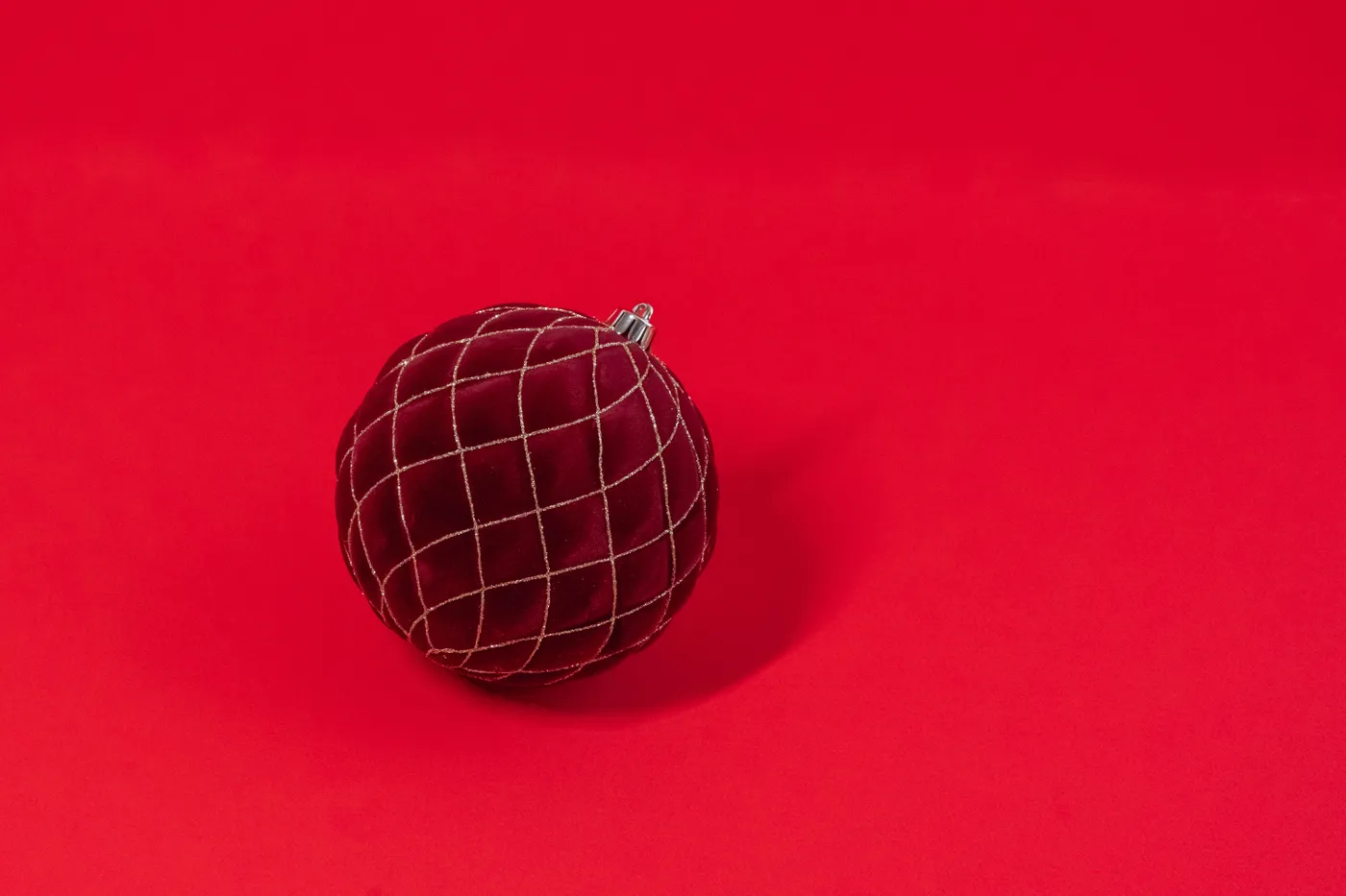 A velvet red Christmas ornament with a grid pattern on a vivid red backdrop, perfect for festive designs.