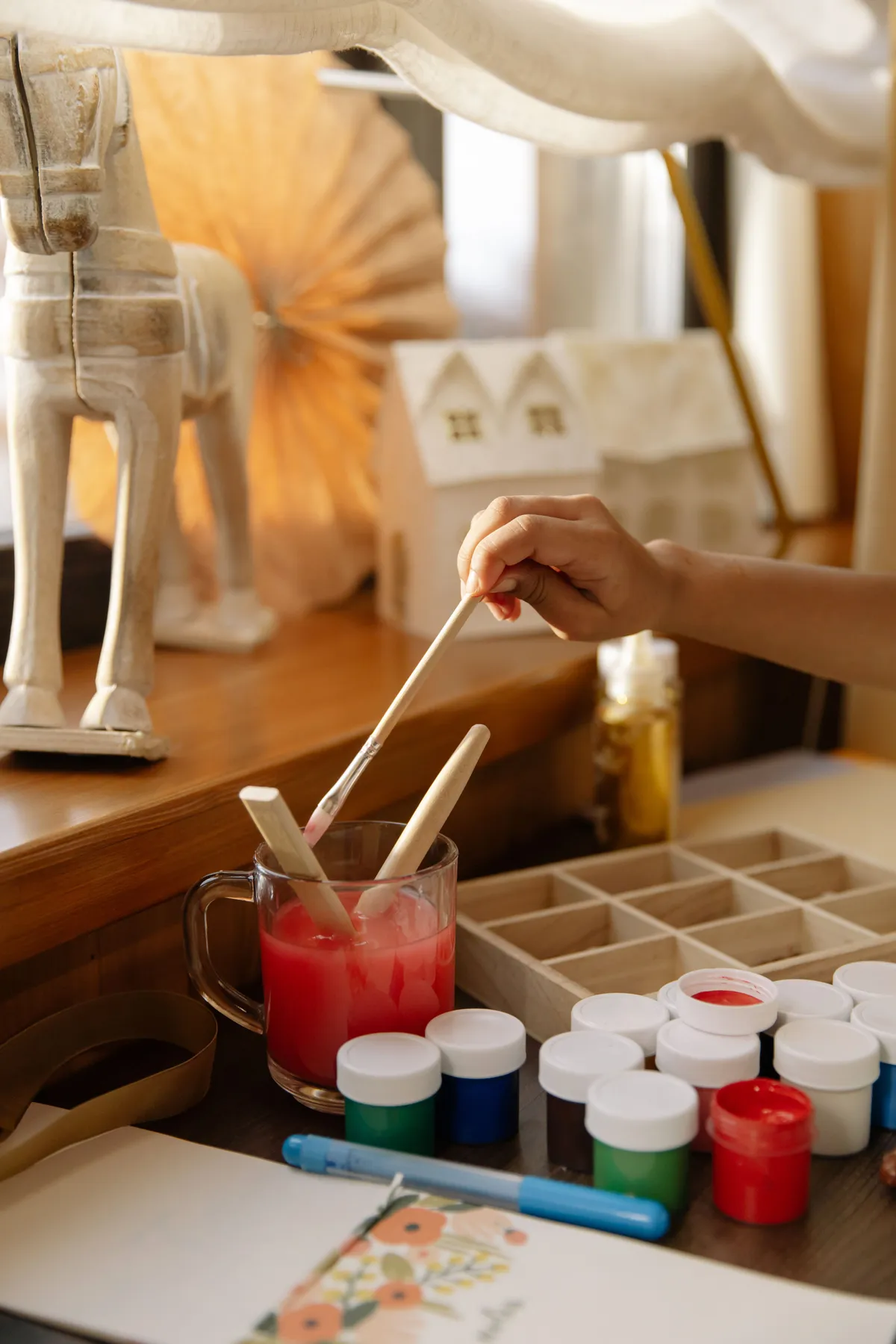 Artist working on a painting project using varied art supplies in a cozy indoor setting.