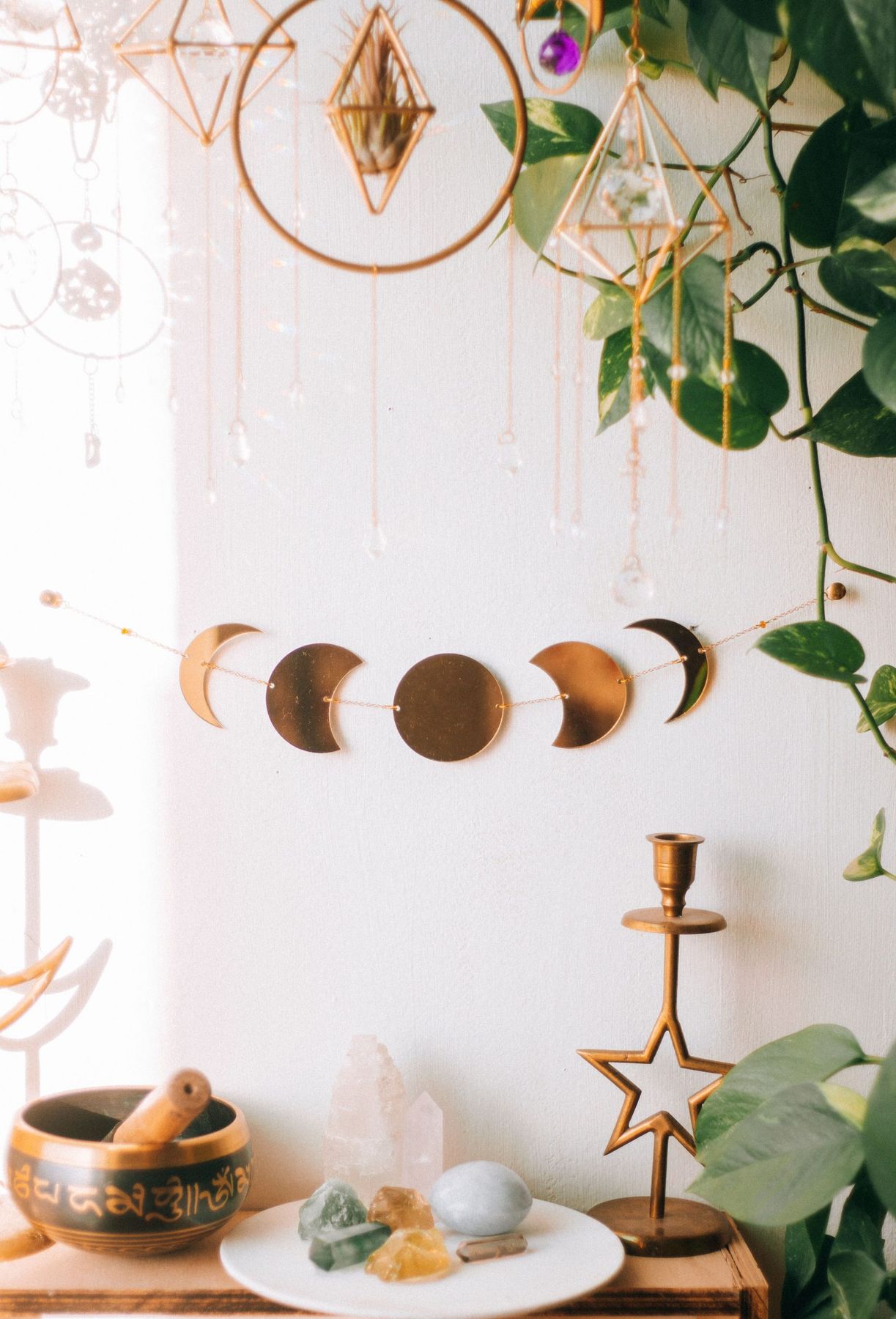 Artistic bohemian interior with moon phase decor, crystals, and lush plants.