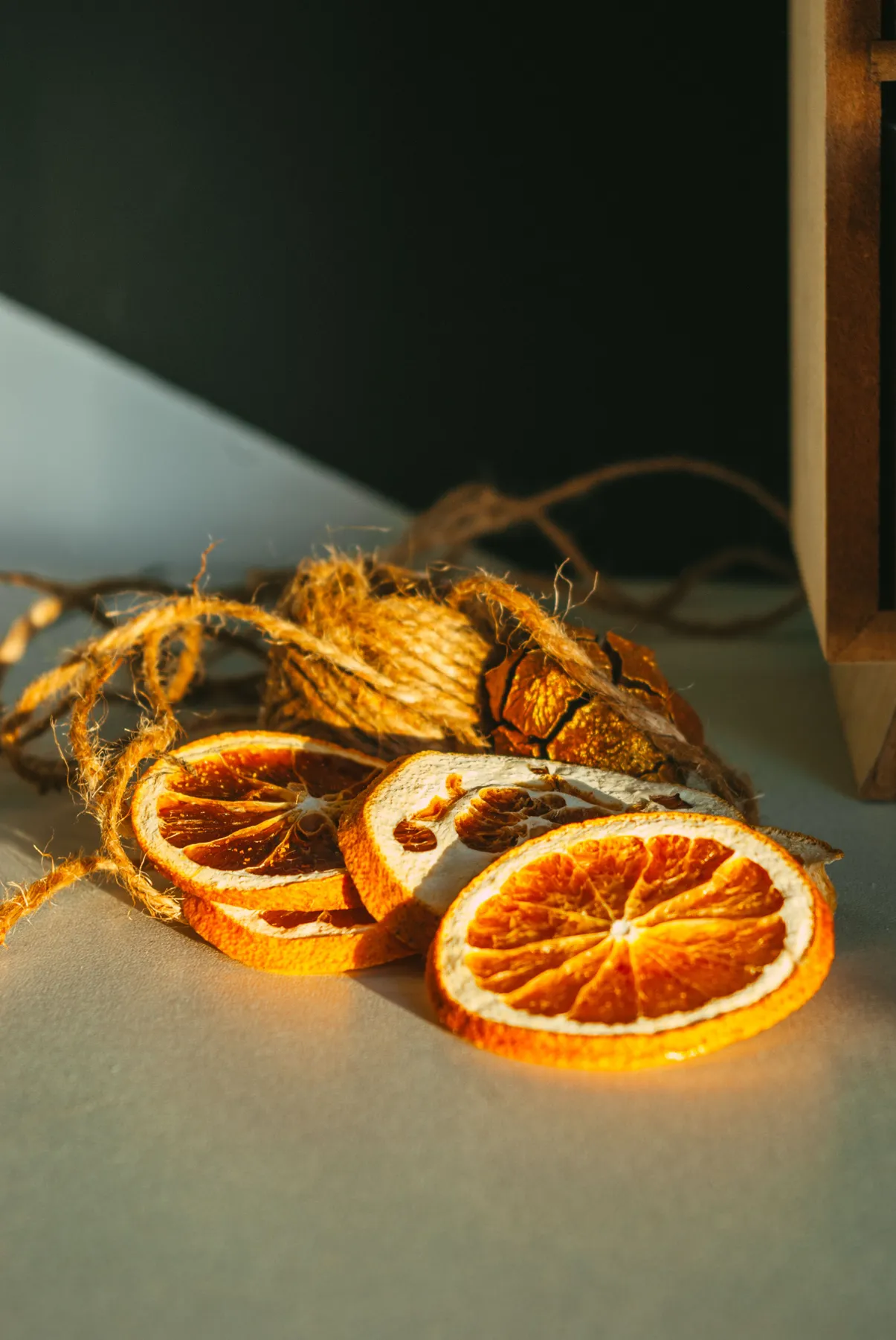 Artistic composition of dried orange slices with twine on a sunlit countertop.