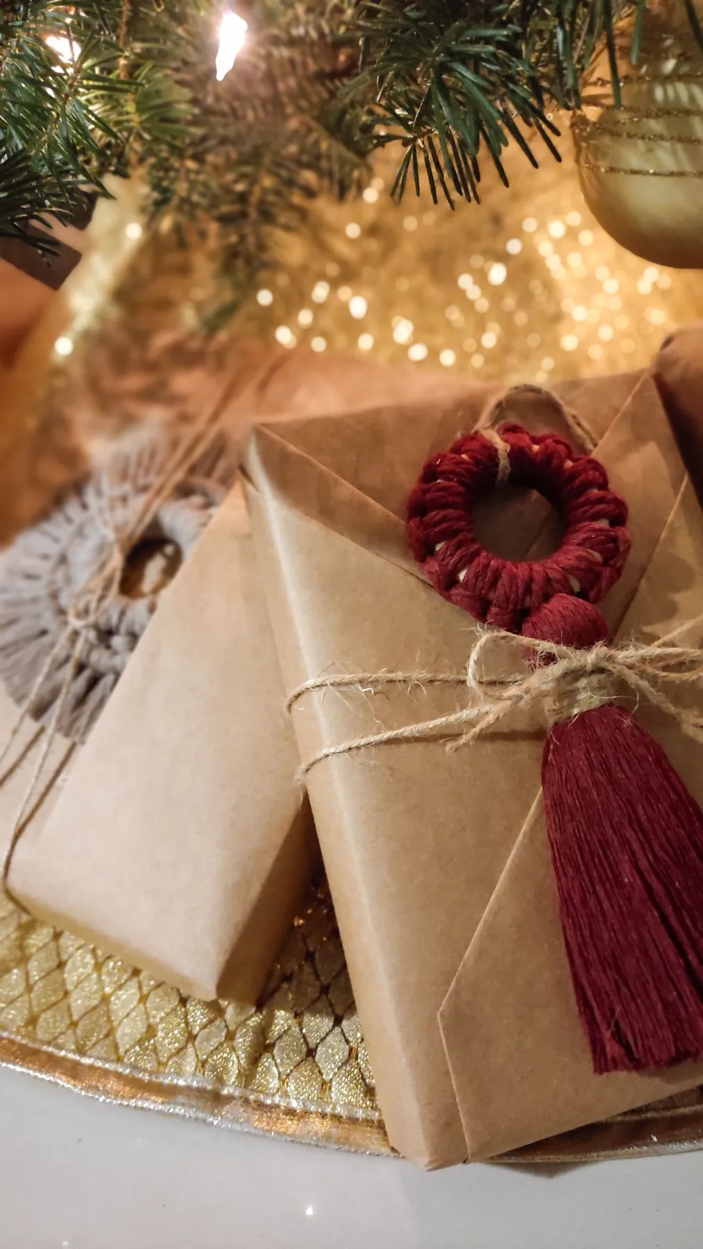 Beautifully wrapped gifts with macrame ornament under a Christmas tree, exuding holiday cheer.