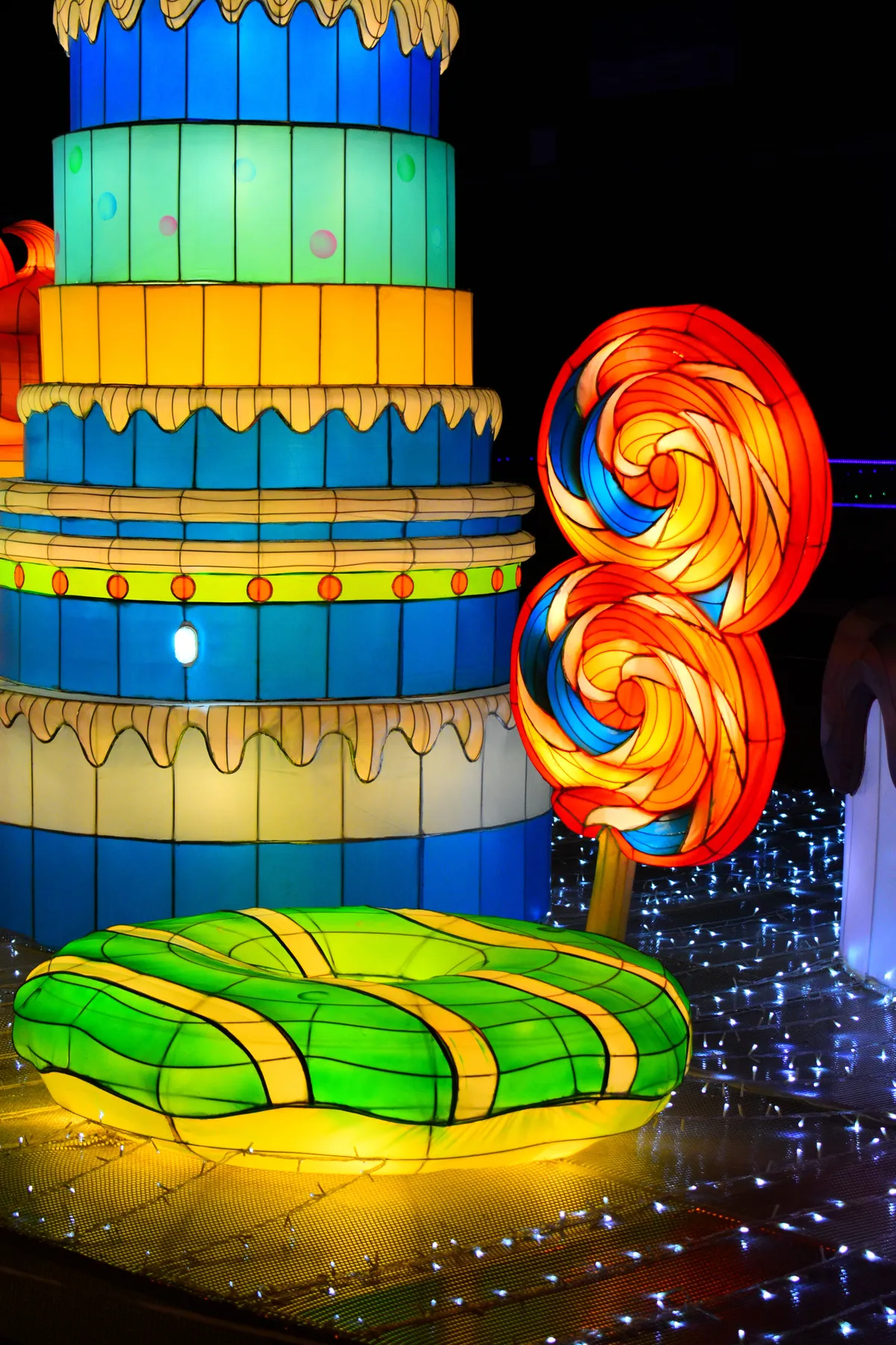 Brightly lit, colorful candy and cake decorations glow in the dark for a festive ambiance.