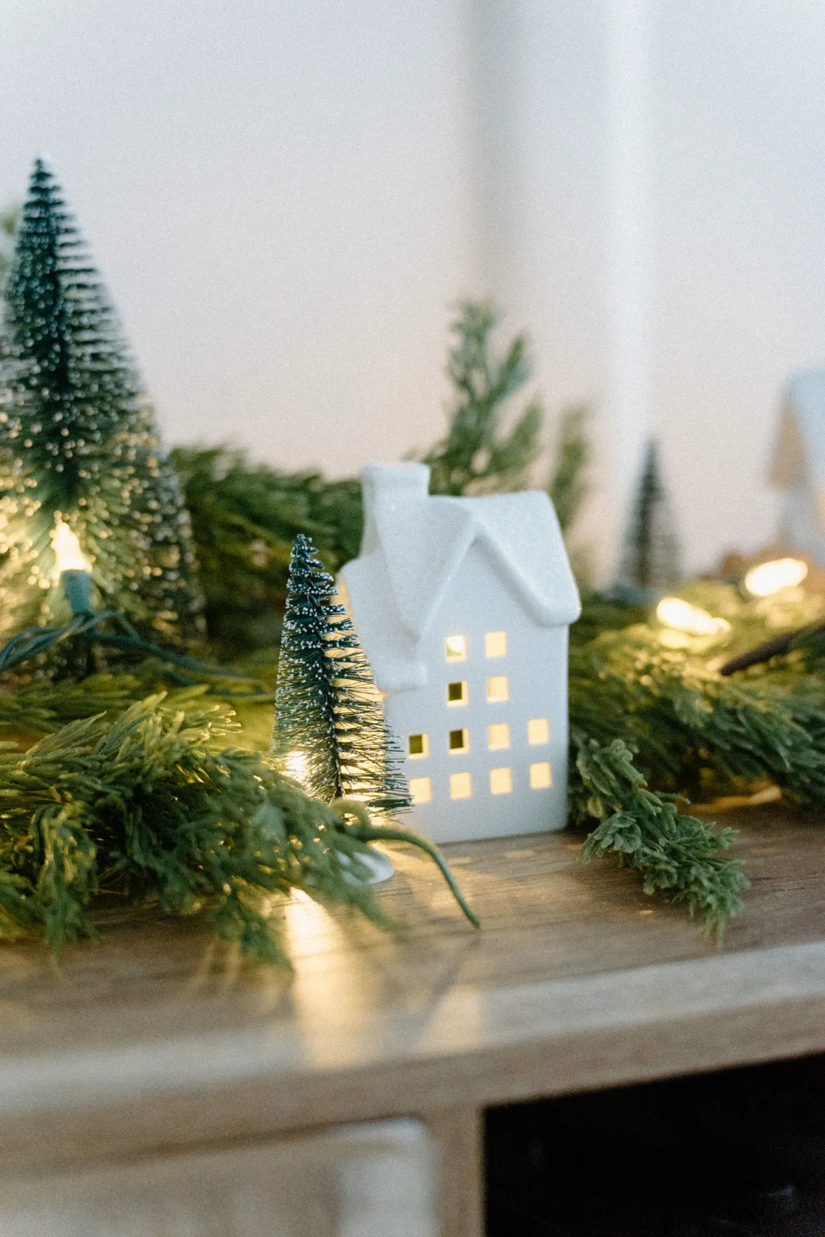 Charming miniature house with festive lights and trees, perfect holiday decor.