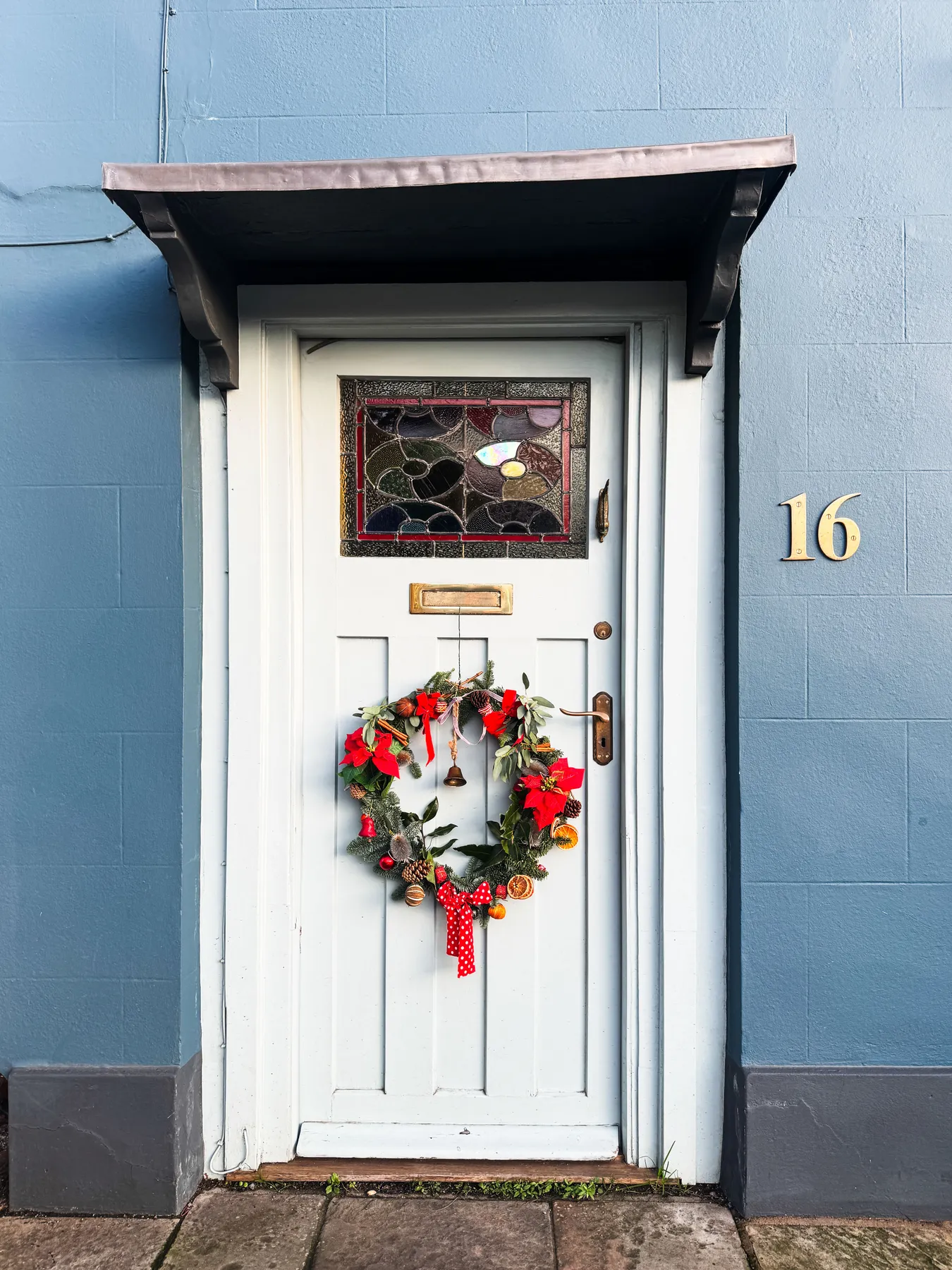 Charming white cottage door with a festive Christmas wreath in Malmesbury, England.