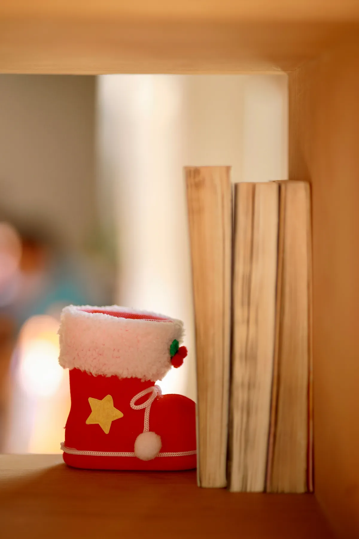 Christmas themed red boot with books on a wooden shelf, warm and festive decor.