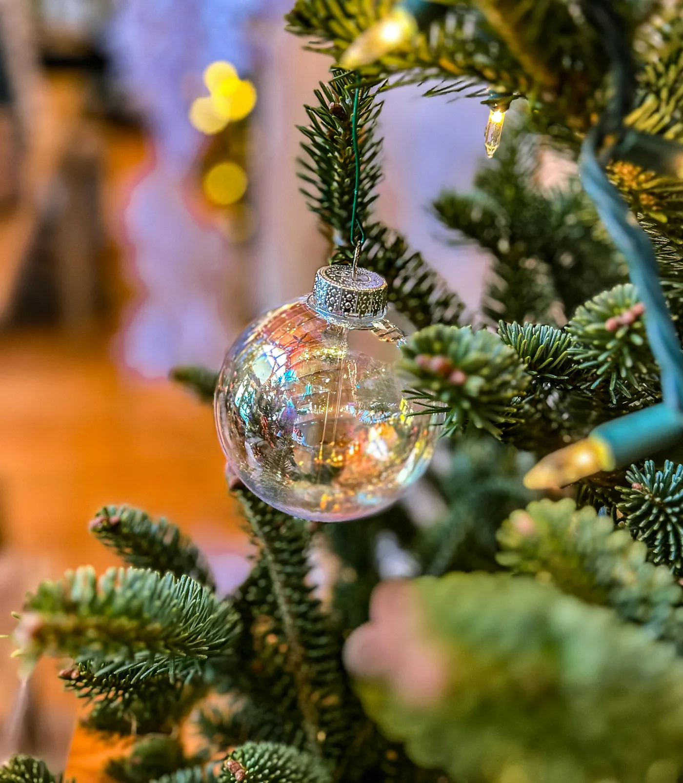 Clear christmas ornament reflecting festive lights on tree