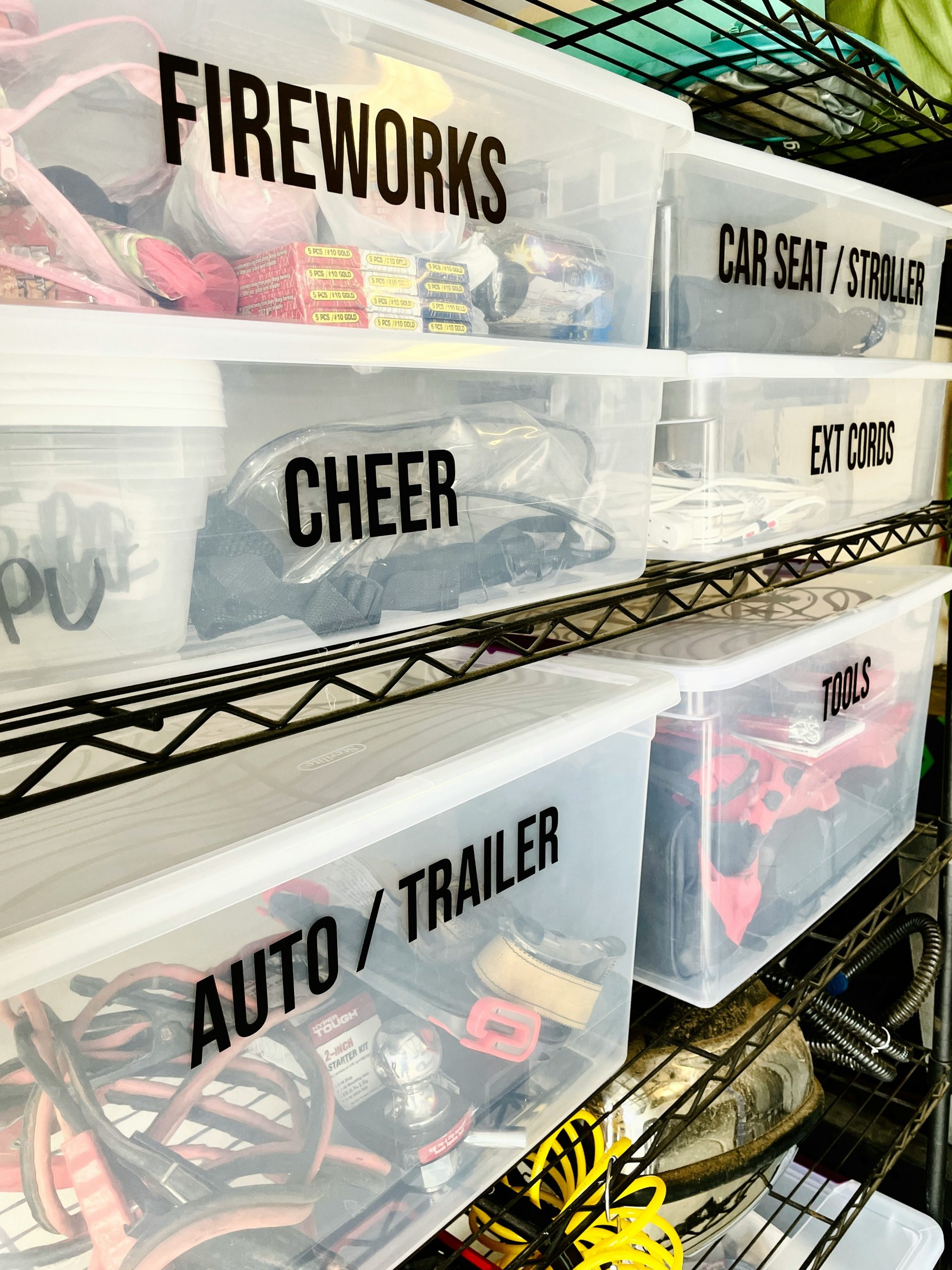 Clear labeled storage bins keep garage essentials like tools, extension cords, and seasonal items organized.