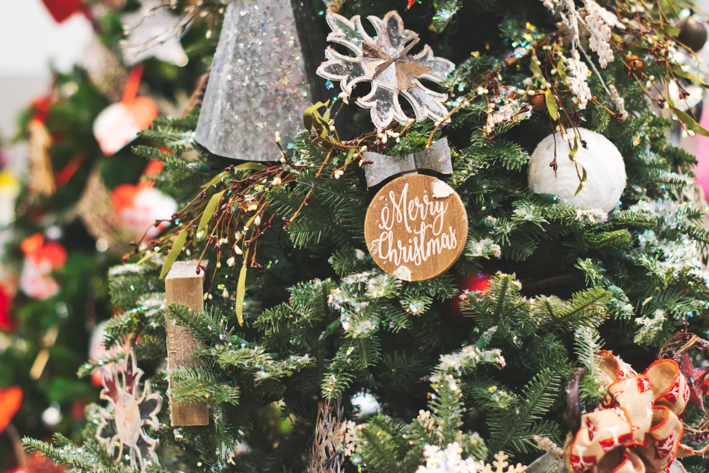 Close-up of a beautifully decorated Christmas tree with festive ornaments and a Merry Christmas sign.
