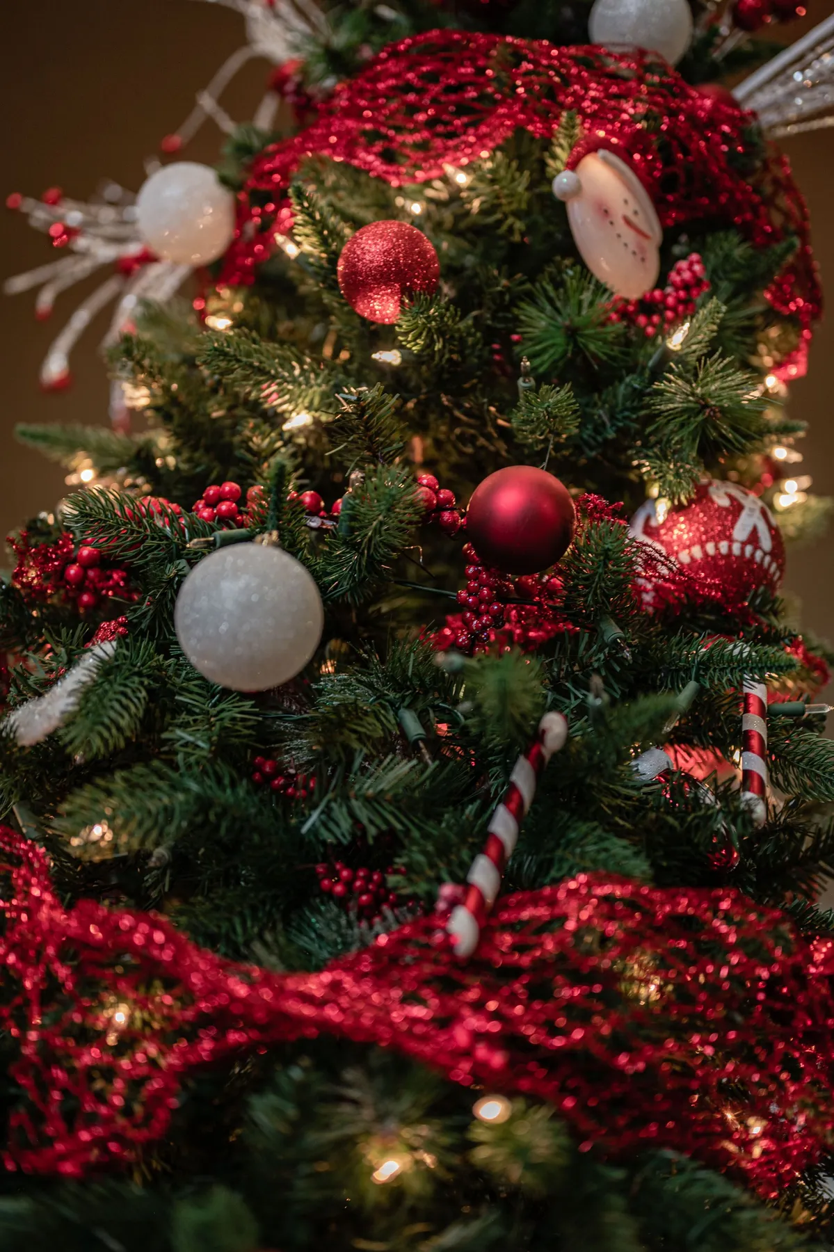 Close-up of a beautifully decorated Christmas tree with red and white ornaments and twinkling lights.