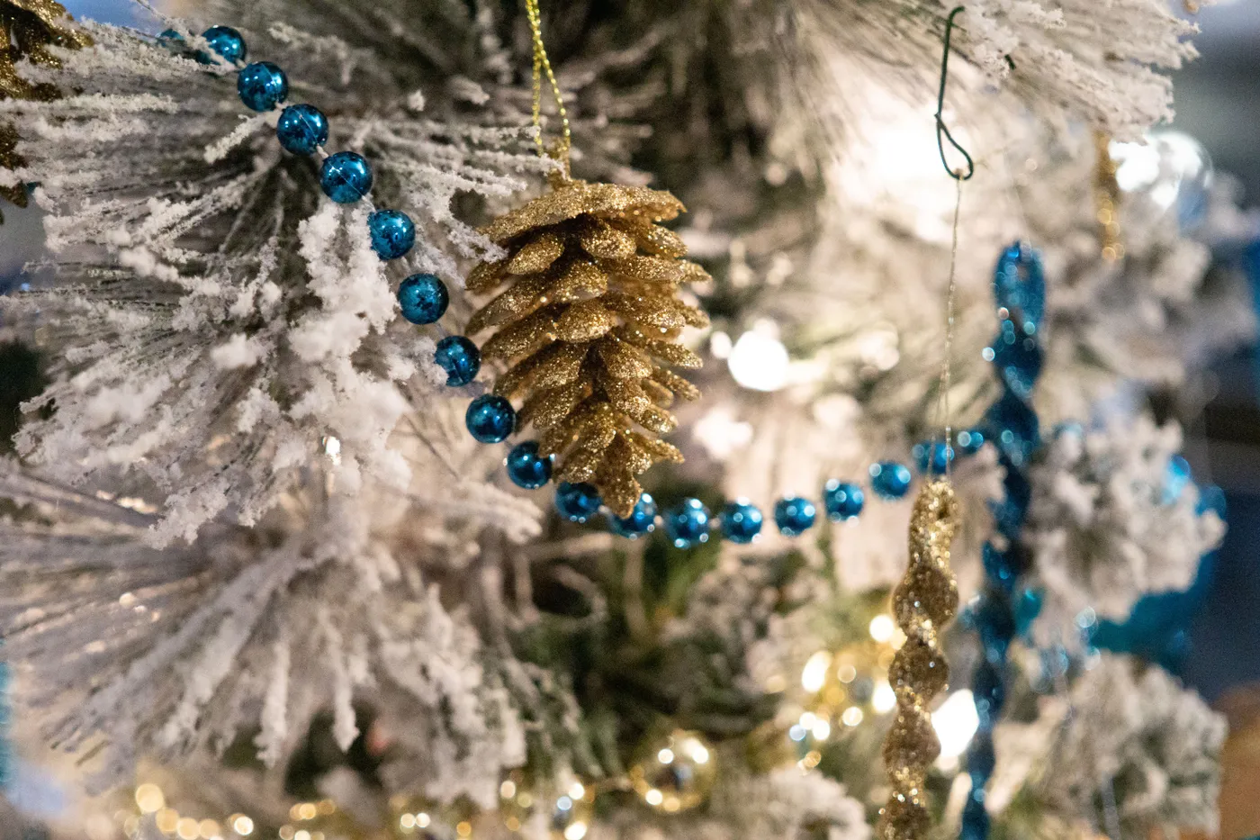 Close-up of a Christmas tree adorned with gold and blue ornaments, evoking holiday cheer.