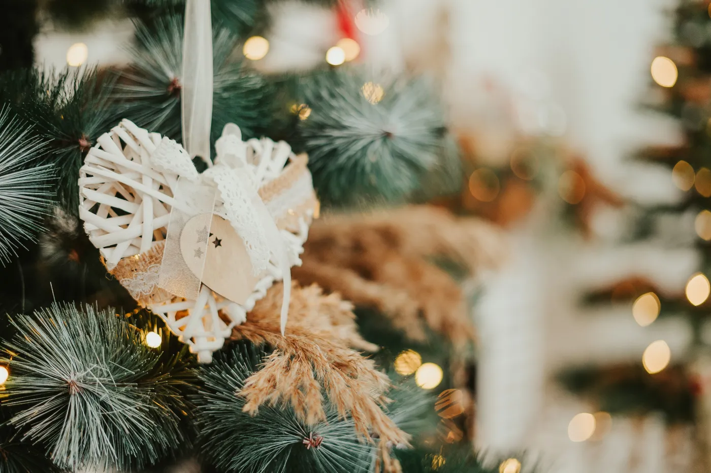 Close-up of a rustic wooden heart ornament hanging on a Christmas tree with soft lights.