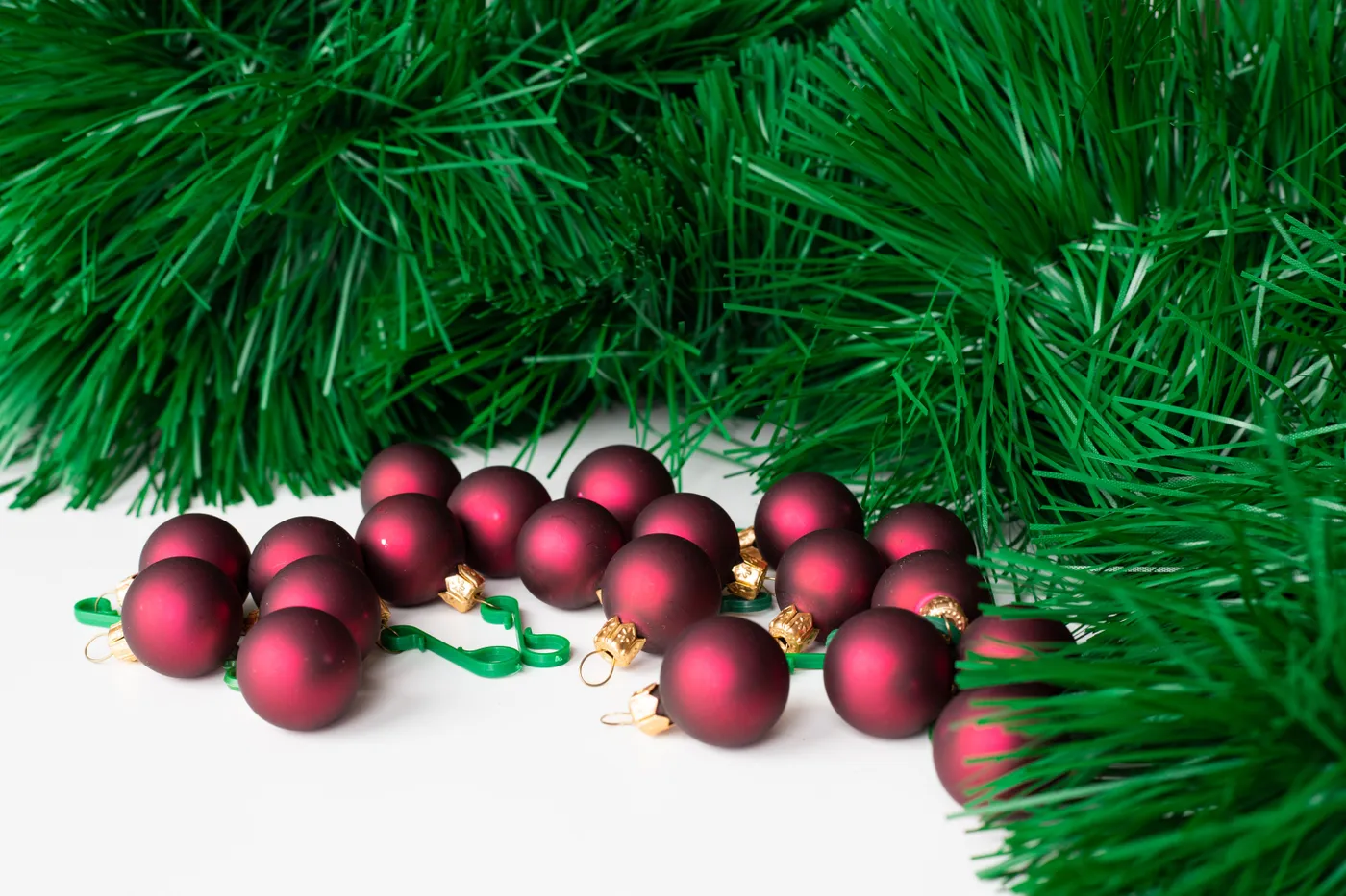 Close-up of red Christmas balls surrounded by green artificial pine branches.