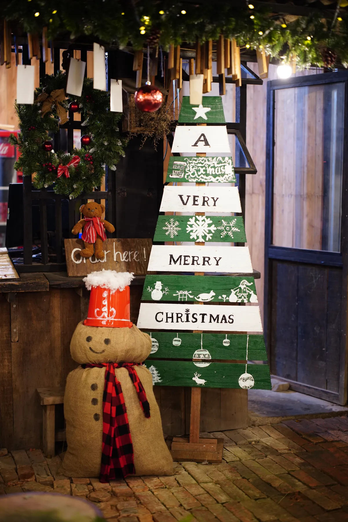 Cozy indoor Christmas scene with a snowman and wooden tree sign.