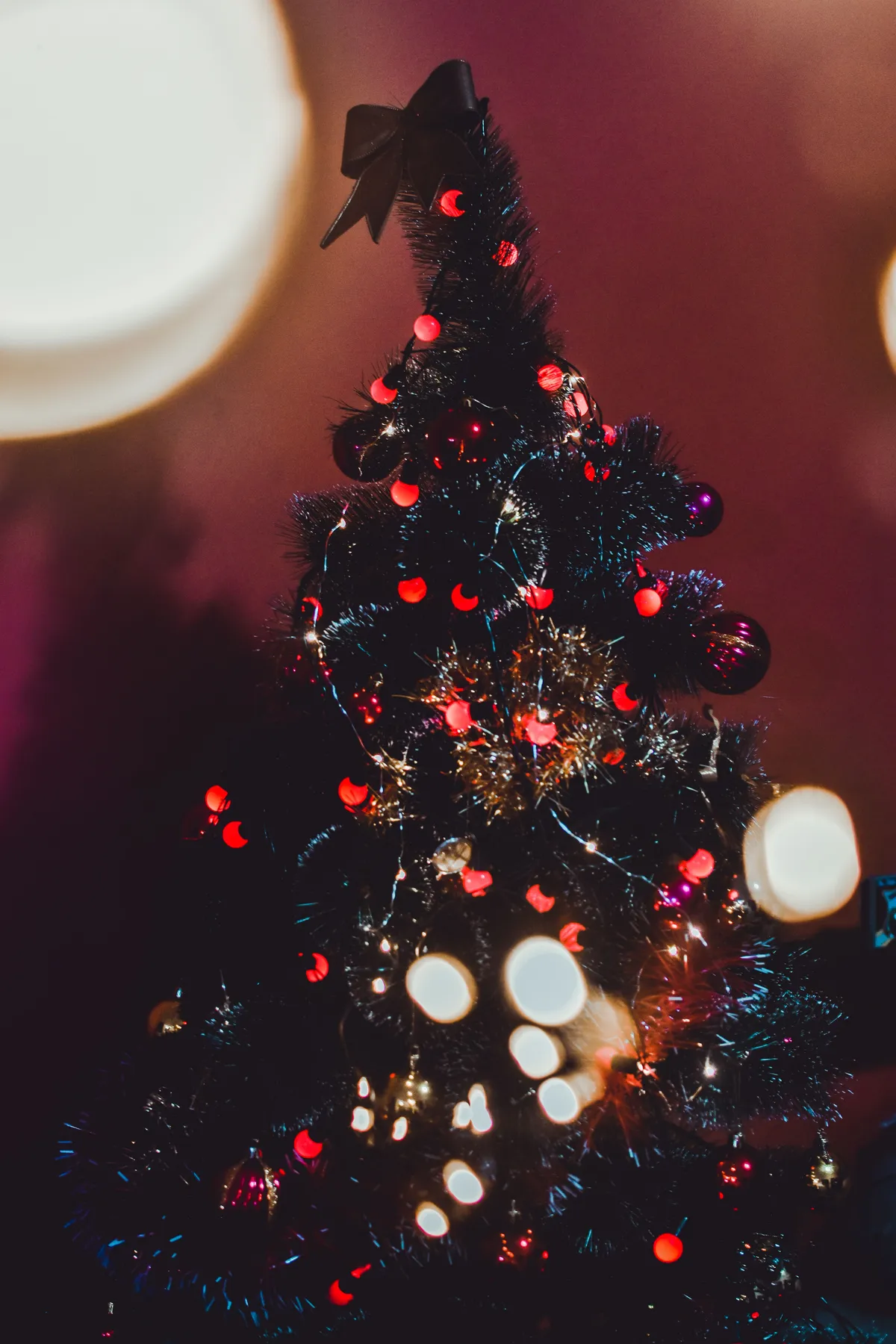Cozy indoor Christmas tree adorned with vibrant lights and ornaments, radiating holiday warmth.