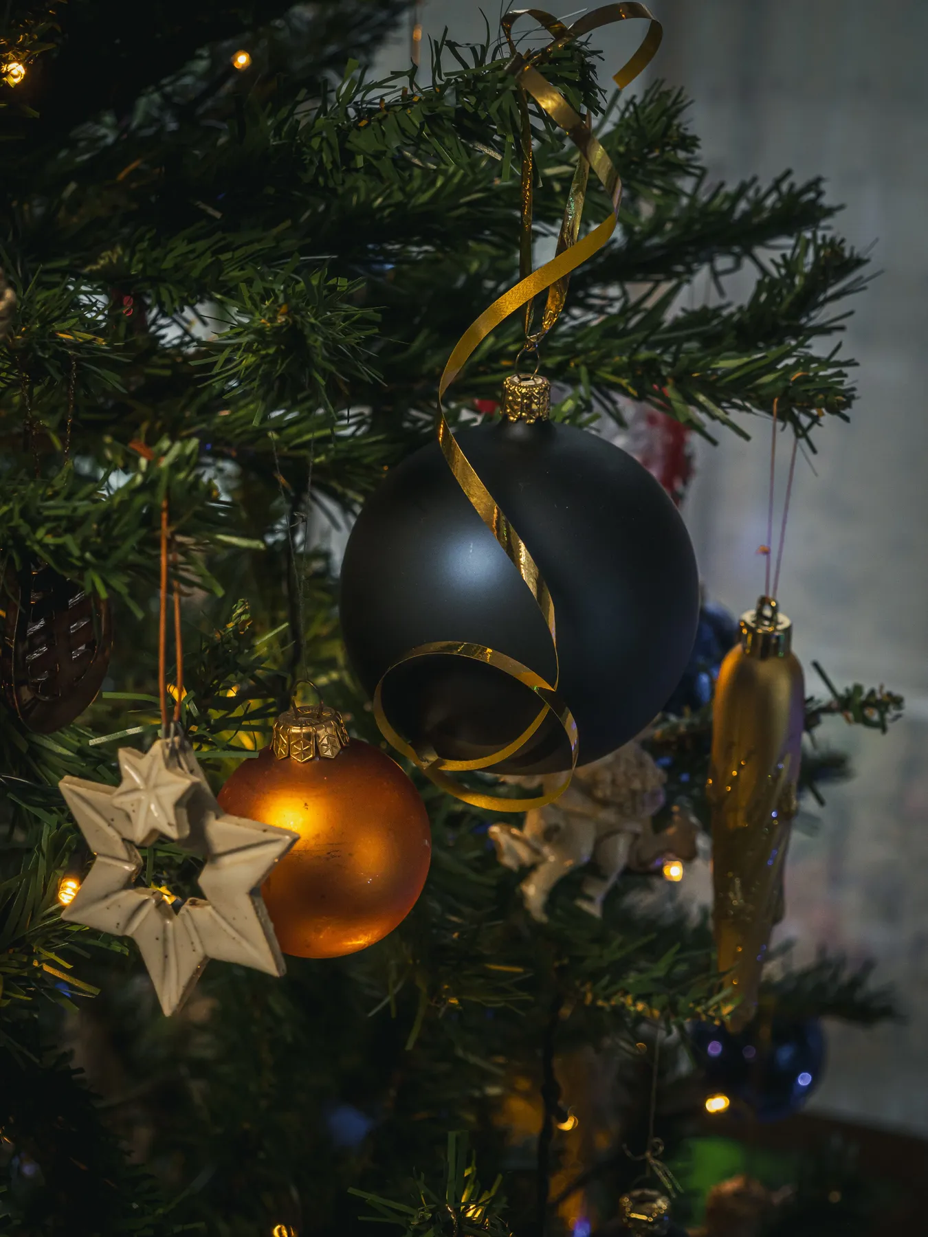 Decorated Christmas tree featuring colorful baubles and star ornaments with holiday lighting.