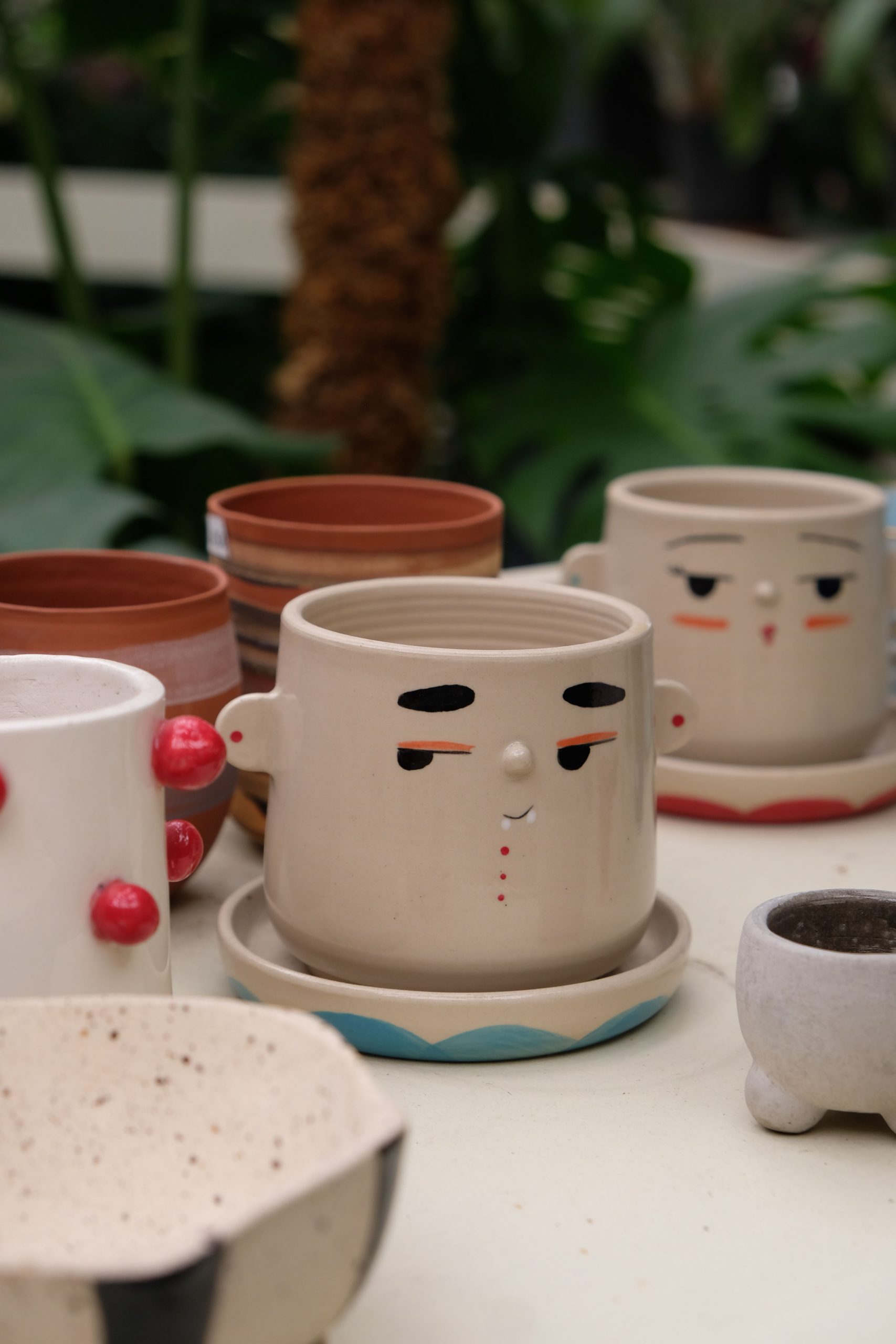 Decorative ceramic planters with playful face designs, set in a garden.