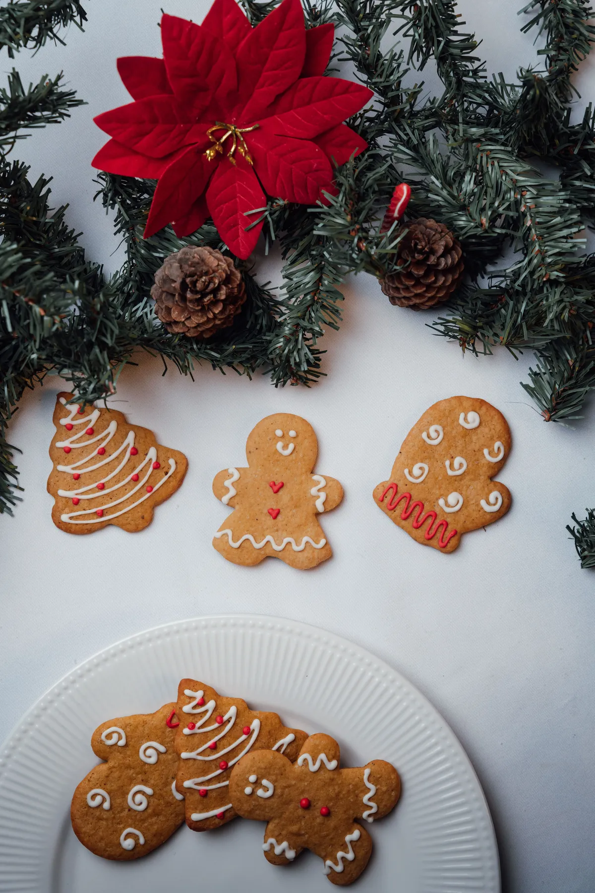 Delightful gingerbread cookies surrounded by Christmas decorations and greenery.