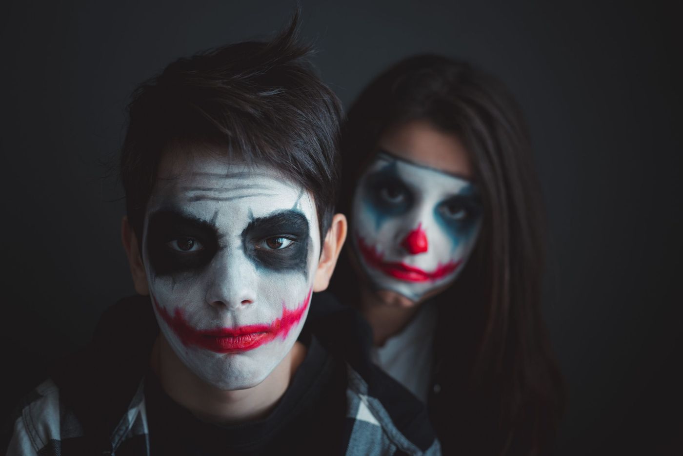 Dramatic portrait of individuals with Joker-inspired face paint, perfect for Halloween themes.