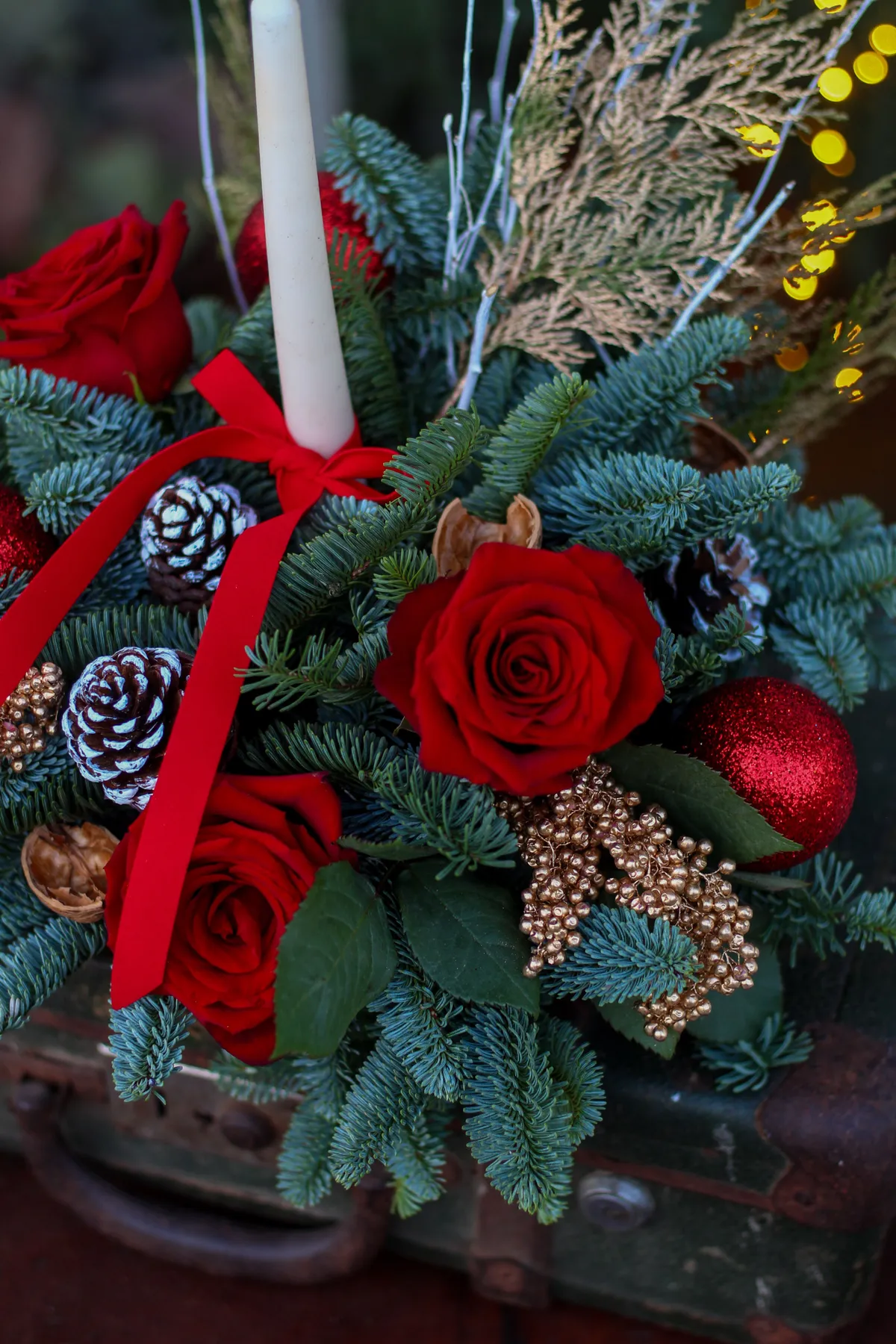 Elegant Christmas arrangement with red roses and pine decorations, perfect for the holiday season.