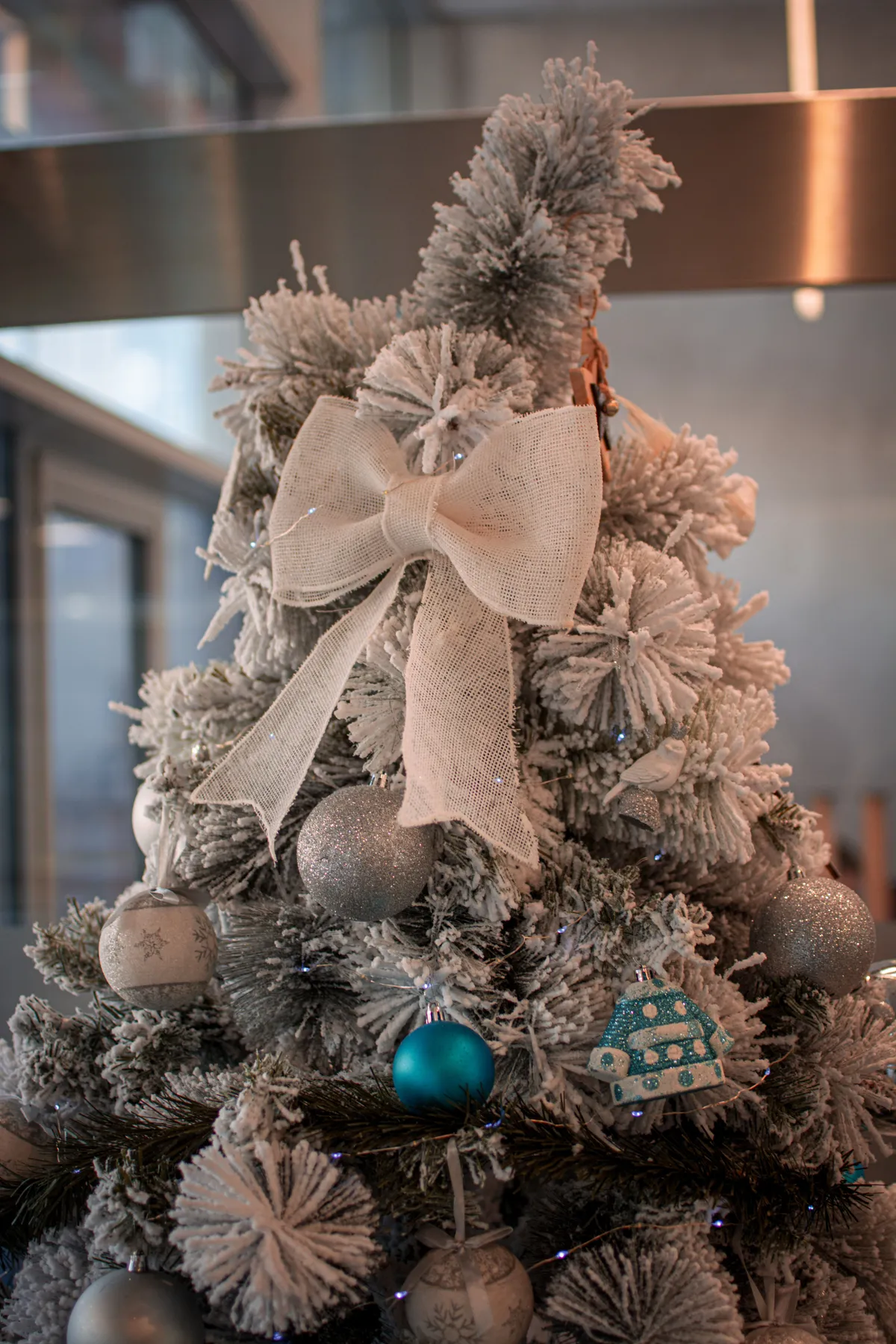 Elegant Christmas tree adorned with glittering ornaments, bows, and snowflakes indoors.