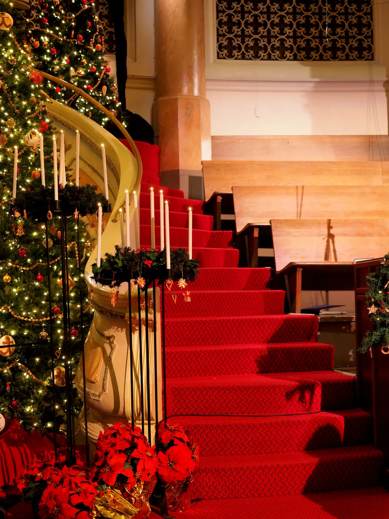Elegant church interior with Christmas tree, red carpet, and candle decor creating a festive atmosphere.