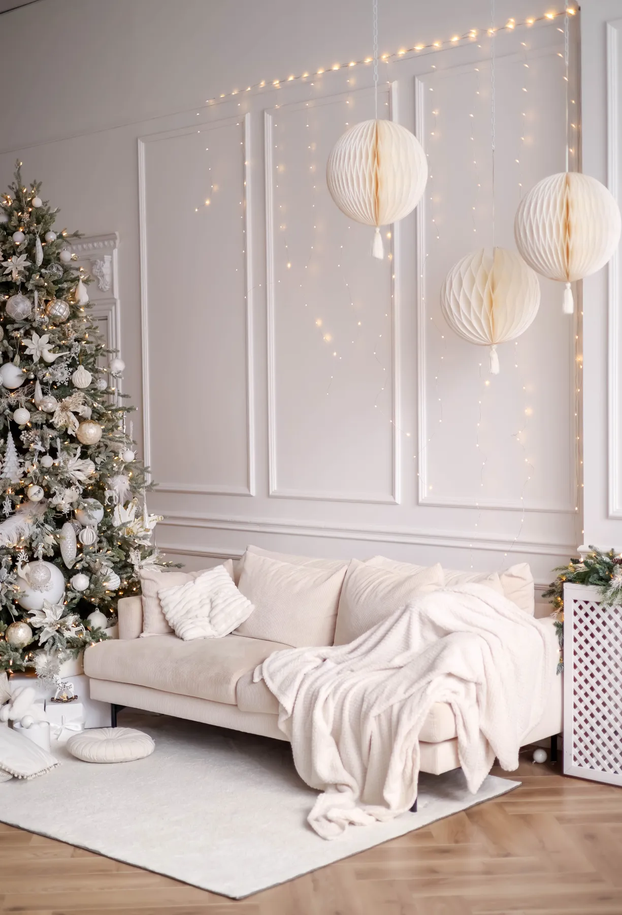 Elegant holiday living room with a white Christmas tree and cozy sofa setup.