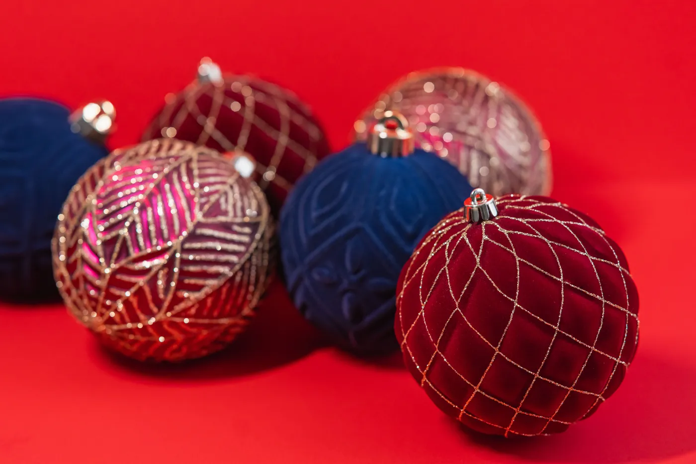 Elegant holiday ornaments displayed against a red backdrop, perfect for seasonal decoration themes.