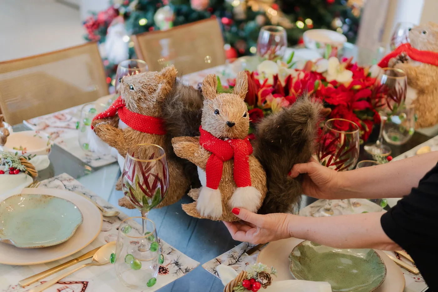 Elegant holiday table setting with festive squirrel decorations and floral centerpiece.