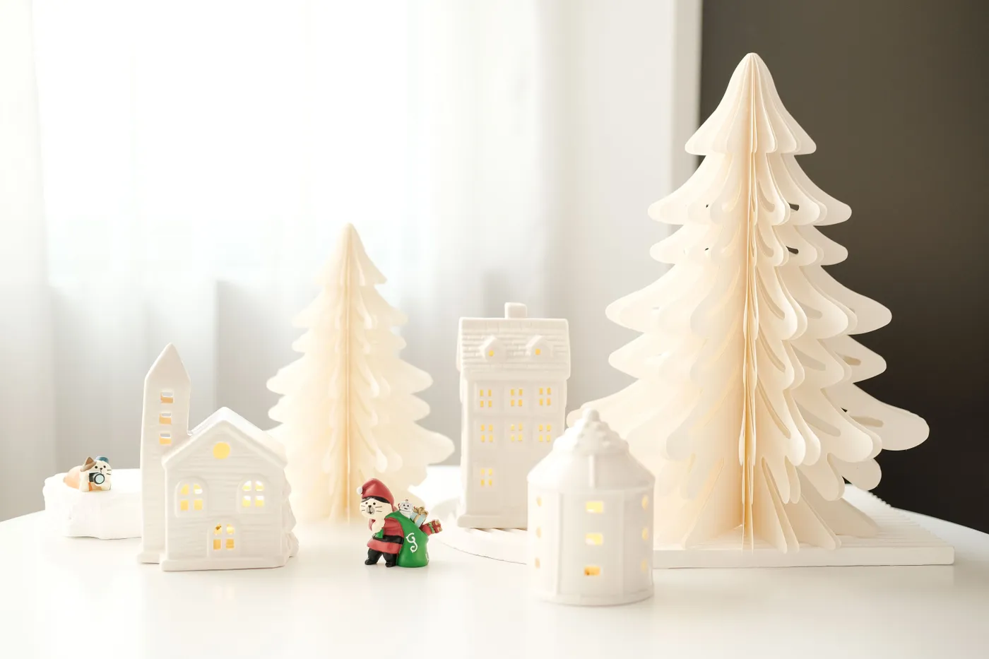 Elegant minimalist Christmas decor featuring paper trees and village houses with soft lighting.