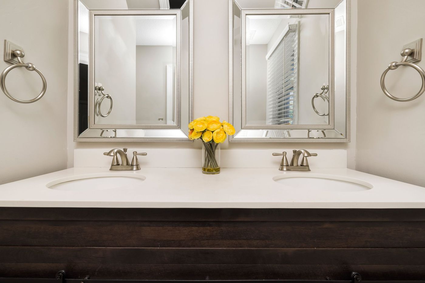 Elegant modern bathroom with twin mirrors, stylish faucets, and a touch of luxury with yellow flowers.