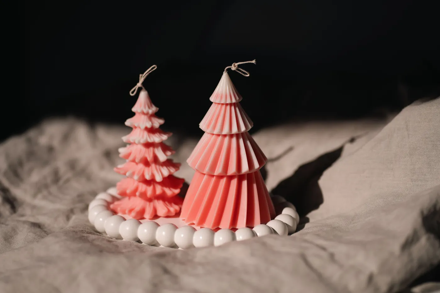 Elegant pink Christmas tree candles on soft fabric, perfect for festive home decor.