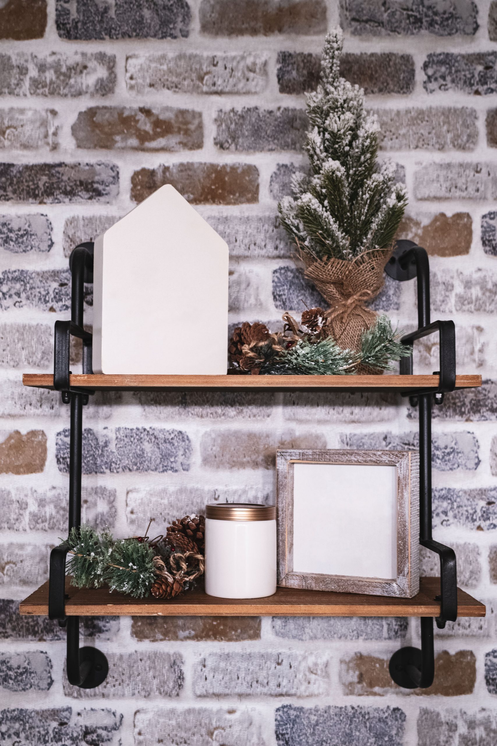 Festive Christmas decorations on wooden shelves against a brick wall create a cozy ambiance.