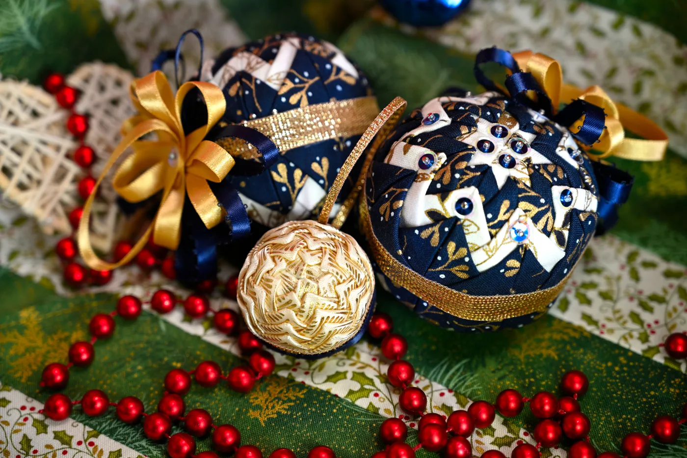 Festive Christmas ornaments with intricate beadwork on a lush green background.