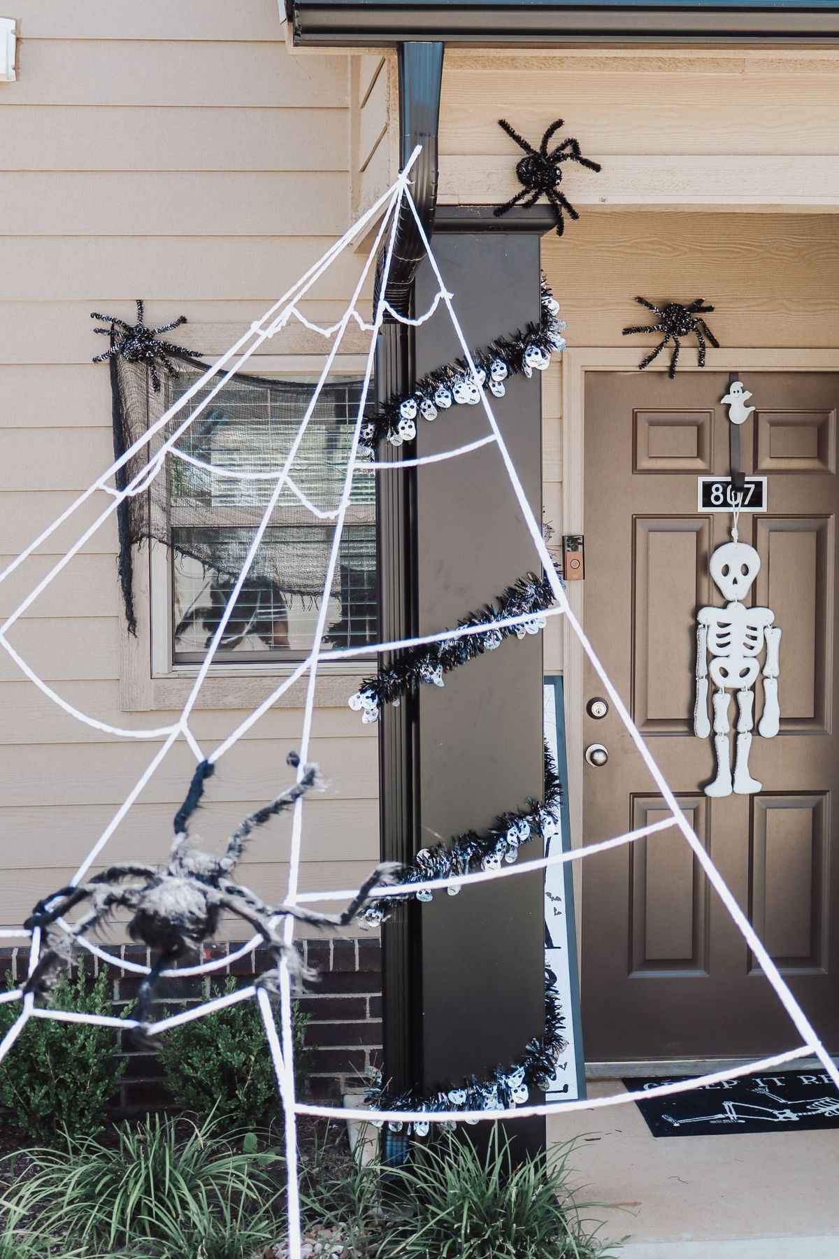 Festive Halloween porch setup with spider webs and a skeleton decoration.