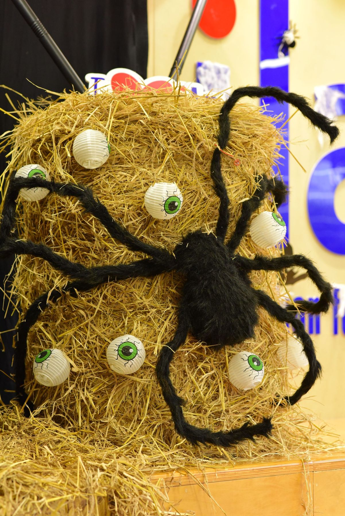 Halloween display featuring a giant spider on a hay bale with eyeball decorations.